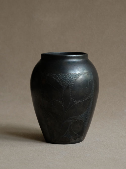 Front view of a compact Art Deco black ceramic vase with an incised floral panel and softly squared upper body.
