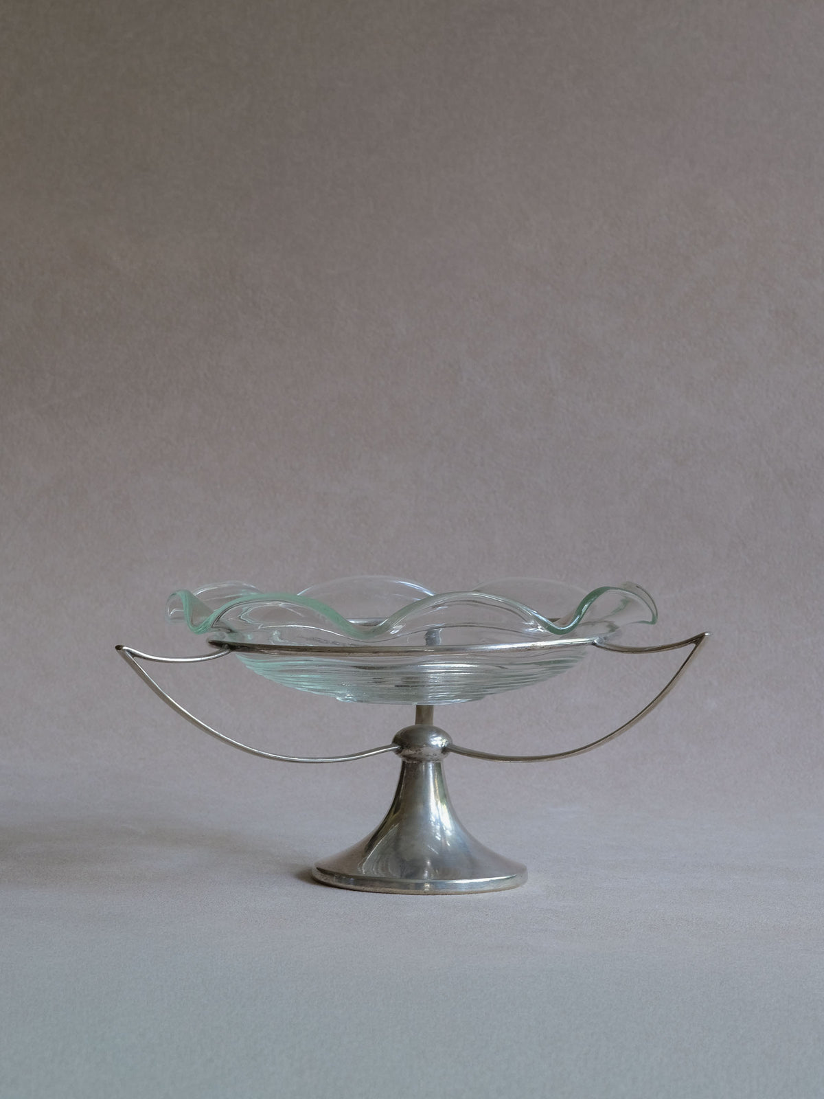 Art Deco clear glass tazza bowl floating above a slender three-arm EPNS silver-plated support, overall view.