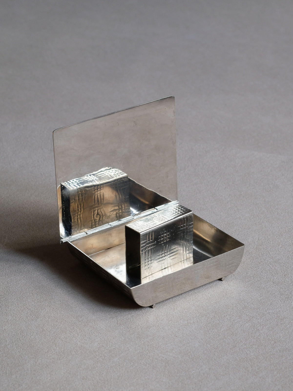 French Art Deco silver-plated table matchbox with a low rectangular form and geometric surface pattern, closed view.