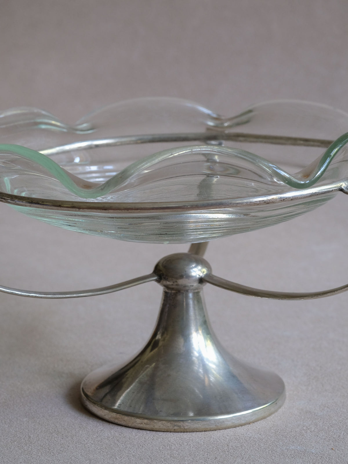Side view of the clear glass tazza bowl showing the visual separation between the bowl and slender EPNS frame.