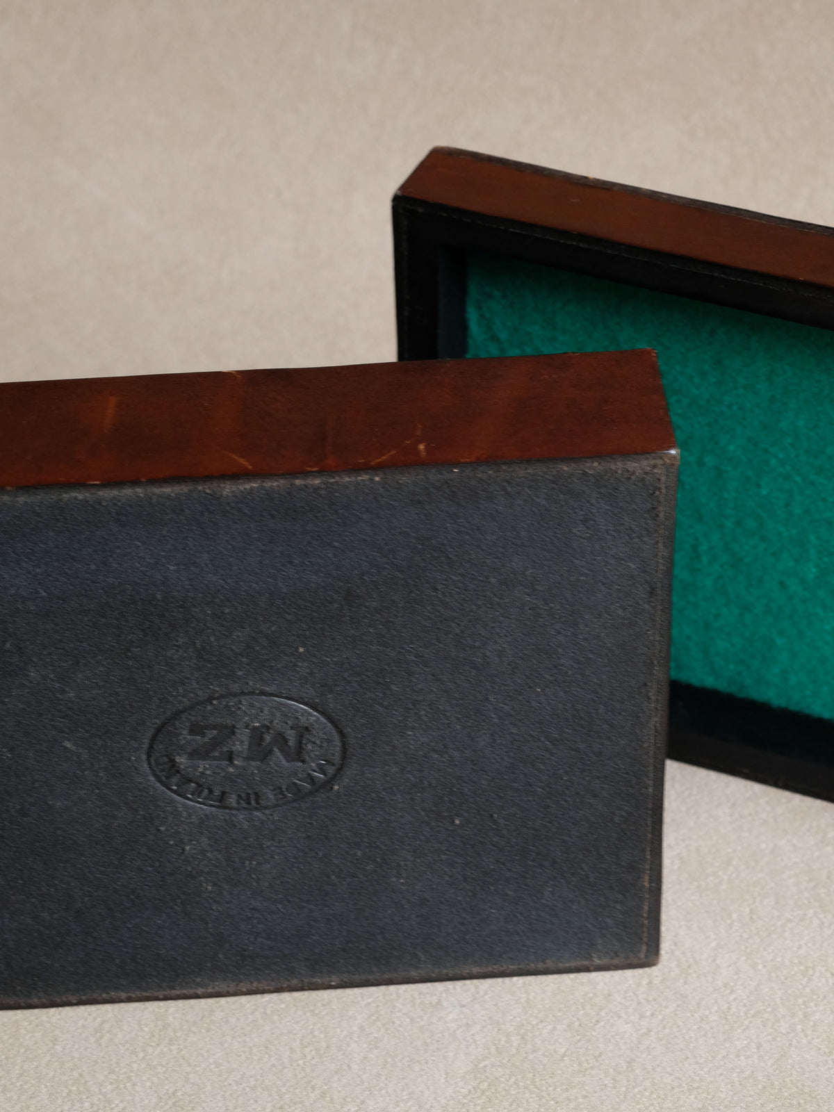 Side view of the burgundy-red leather-wrapped wooden jewellery box showing its depth and sculpted lid surface.