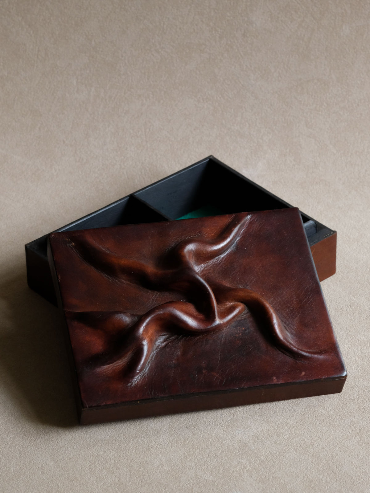 Close view of the deeply modelled leather relief, showing its carved-wood-like sculptural texture.