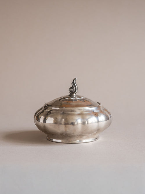 Front view of the silver-plated porcelain lidded sugar bowl, showing the lobed body and small curled finial.