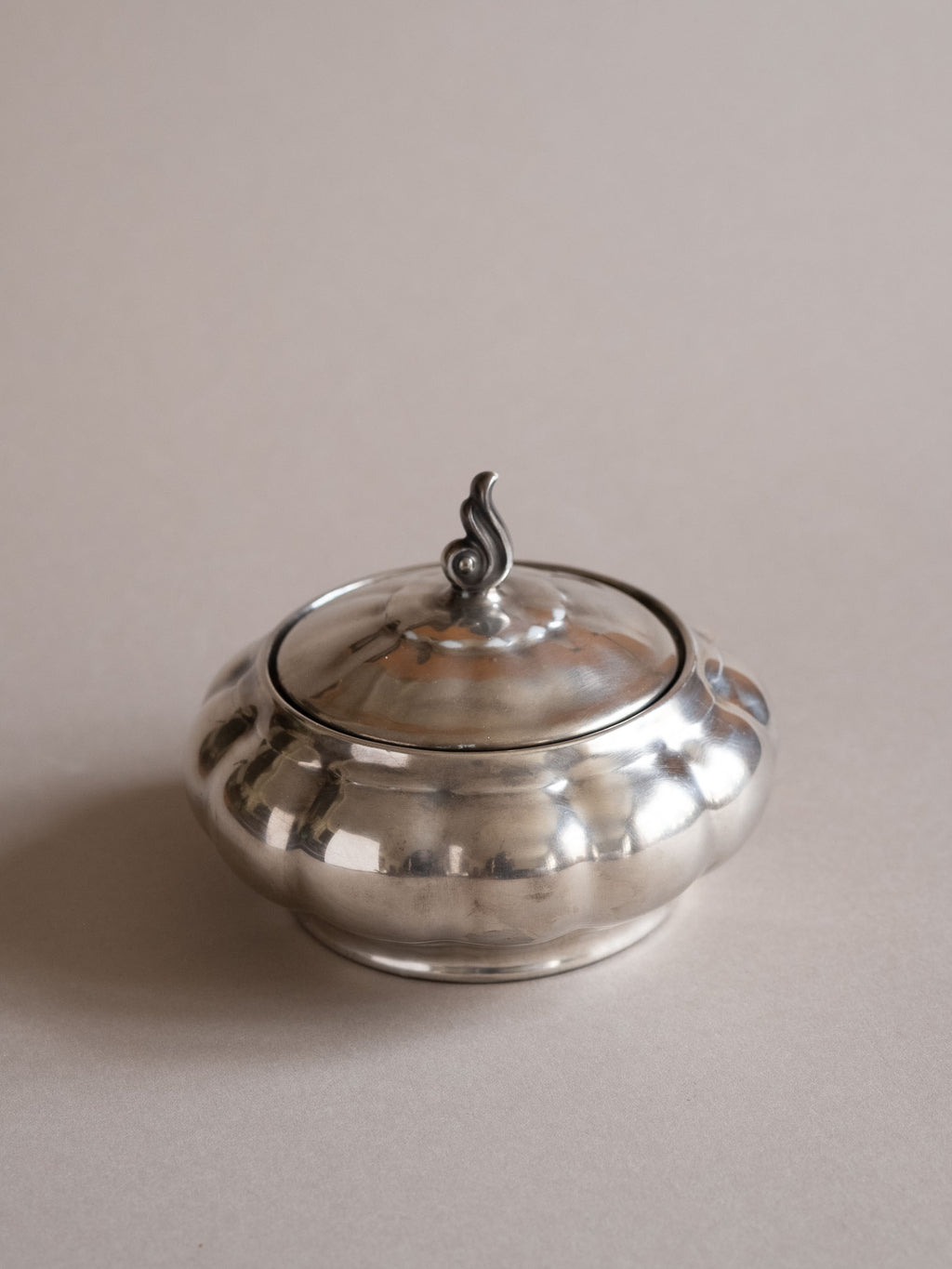 Silver-plated porcelain lidded sugar bowl shown from above at a slight angle, with a lobed body and curled finial.
