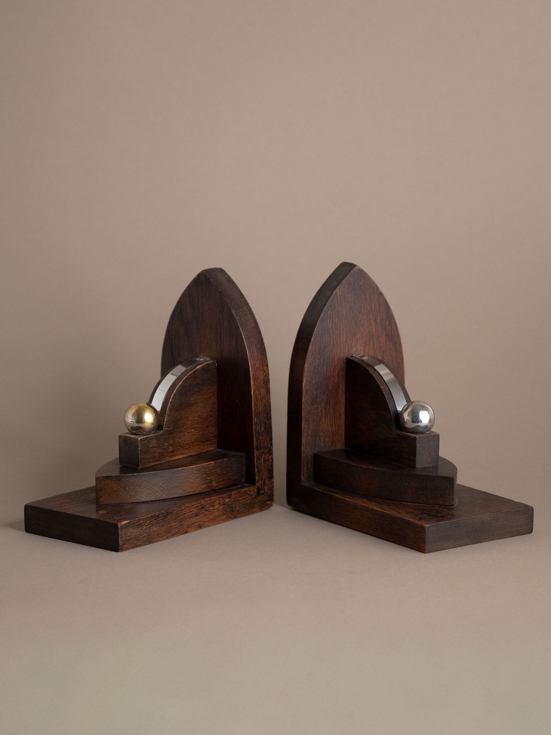 Pair of Amsterdam School oak bookends, Netherlands 1920s–30s, with geometric arched form and nickel-plated brass spheres.
