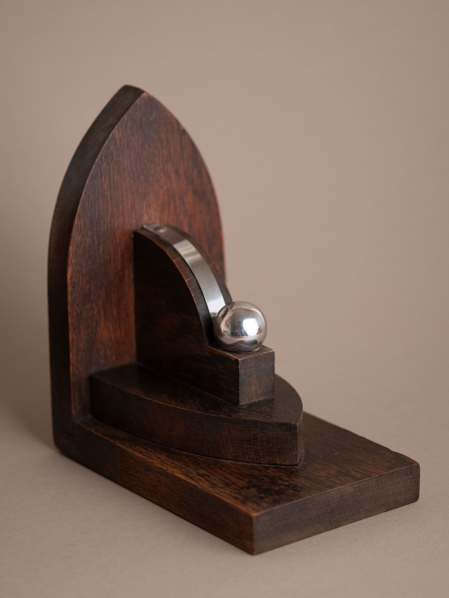 Single Amsterdam School oak bookend, 1920s–30s Netherlands, showing stepped base and nickel-plated brass sphere detail.