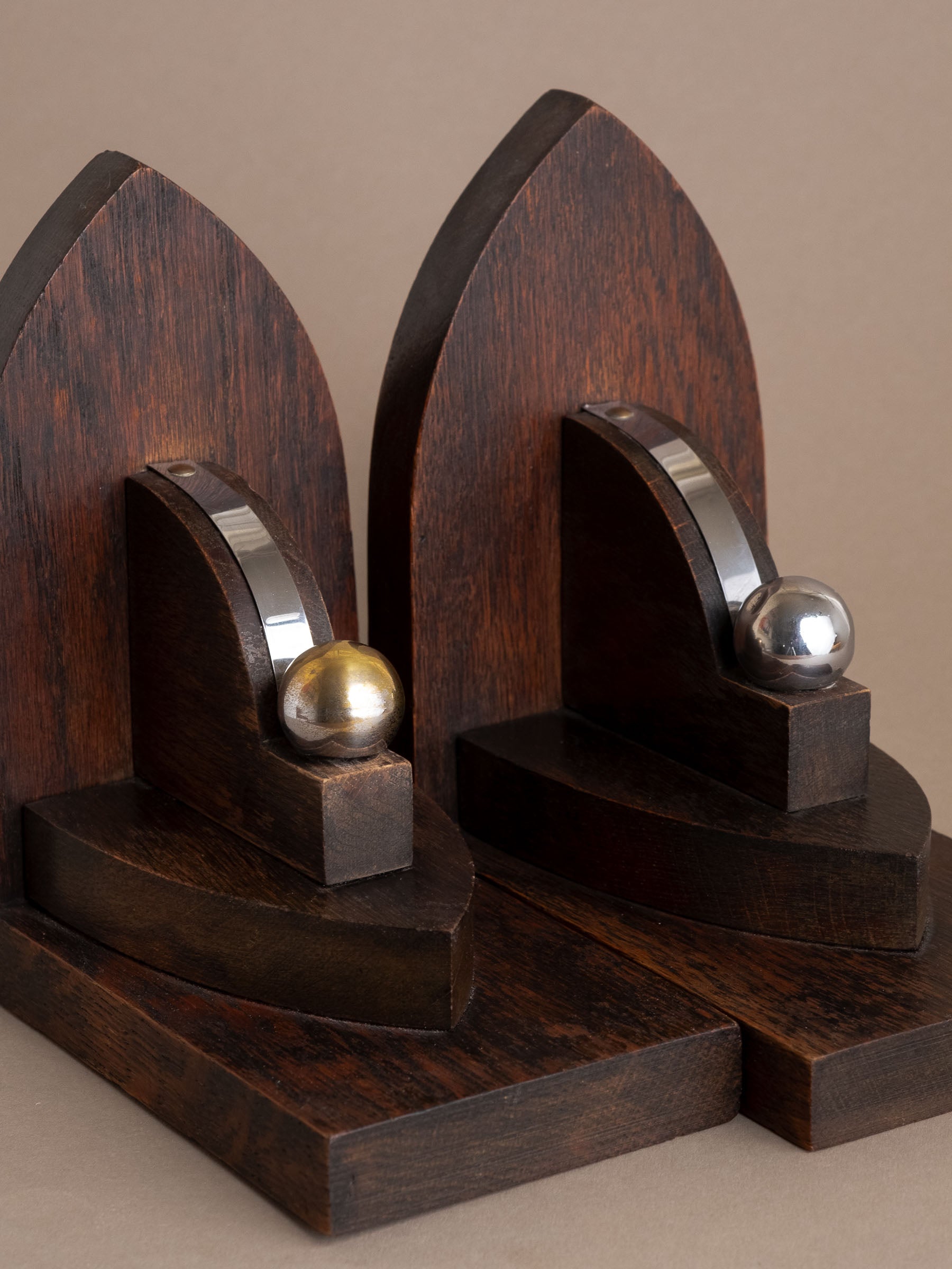 Close-up of Amsterdam School oak bookend showing nickel-plated band and sphere with visible brass beneath.