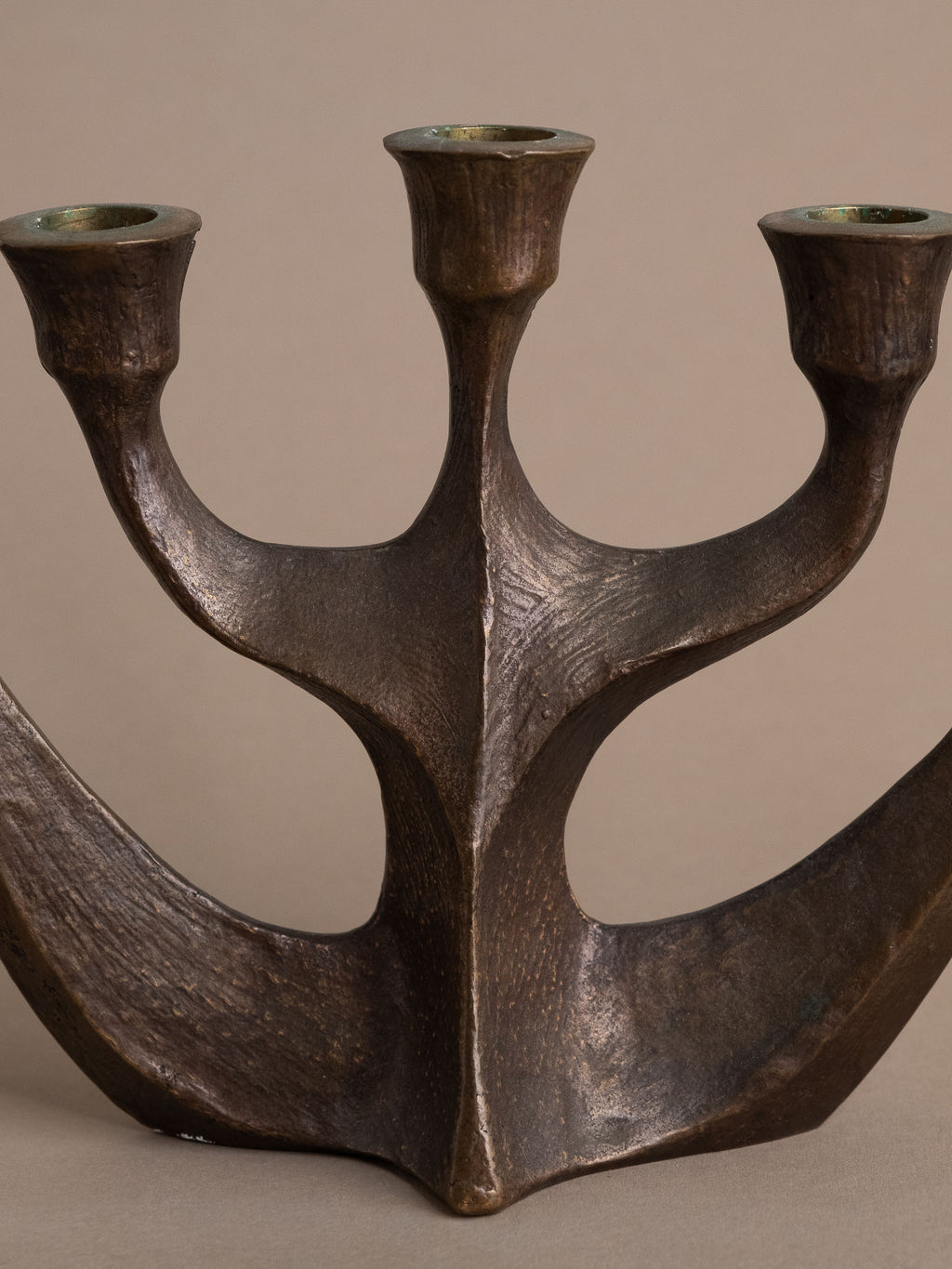 Front detail of central spine and branching arms on Brutalist bronze candleholder.