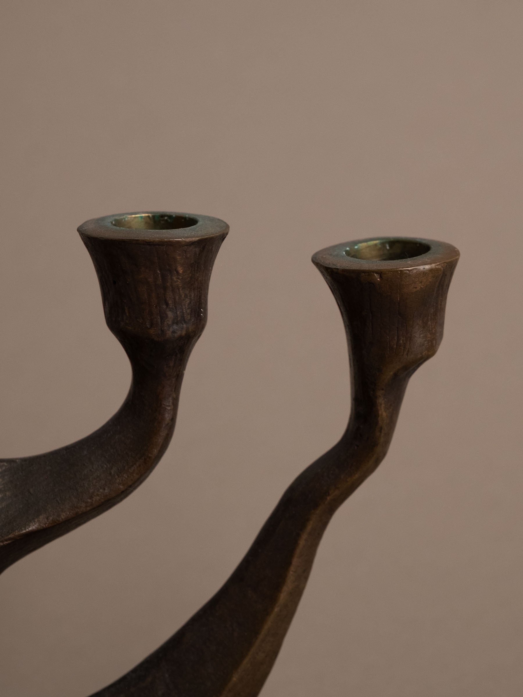 Close-up of candle cups with dark bronze patina on five-arm Brutalist candleholder.