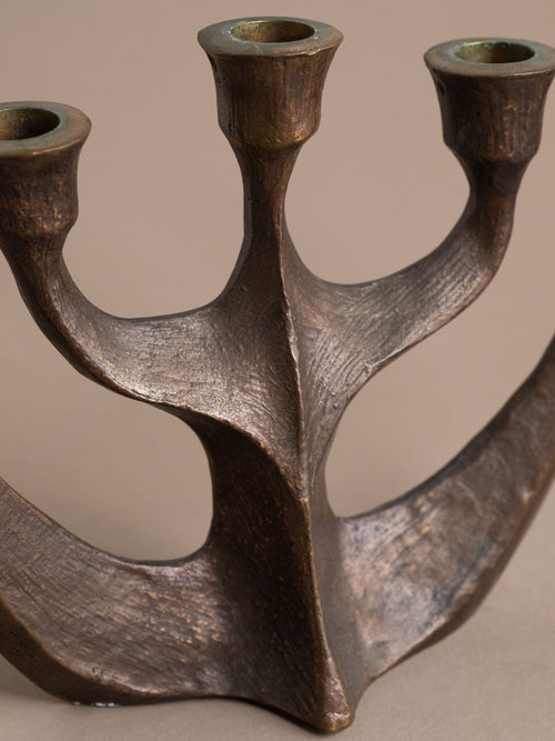 Side view of a Brutalist cast bronze five-arm candleholder by Horst Dalbeck, showing flared candle holders, angular arms, and a heavy textured surface.