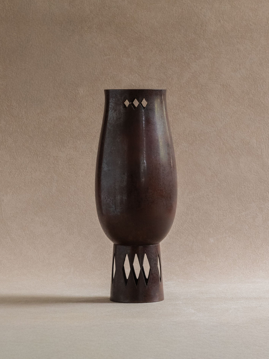 Full view of a Japanese Takaoka cast copper vase with dark reddish-brown patina and diamond openwork at the rim and foot.
