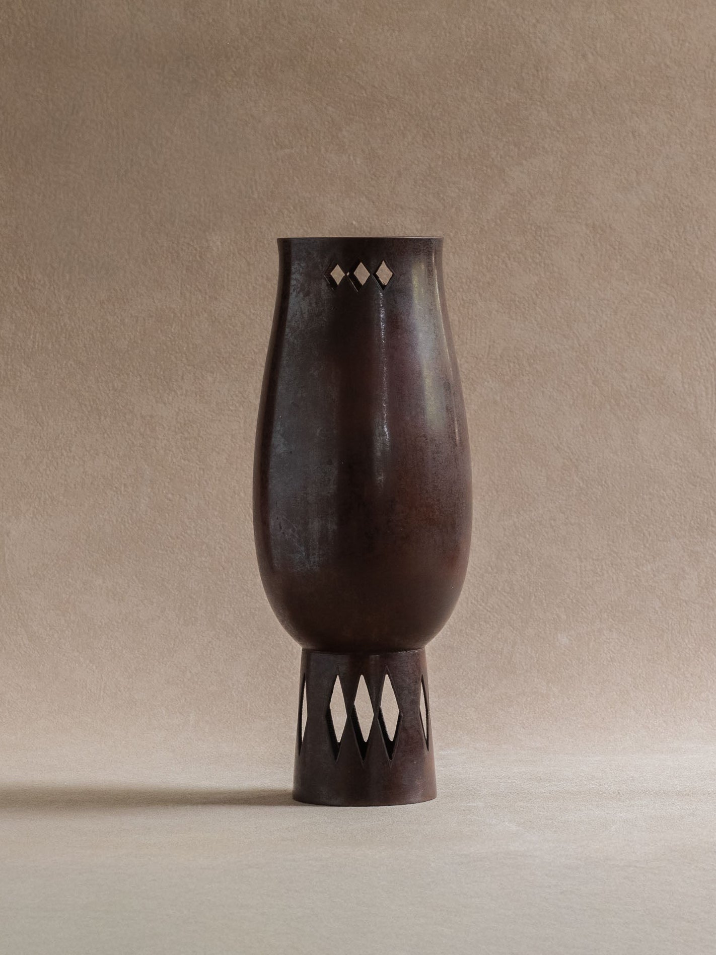 Full view of a Japanese Takaoka cast copper vase with dark reddish-brown patina and diamond openwork at the rim and foot.
