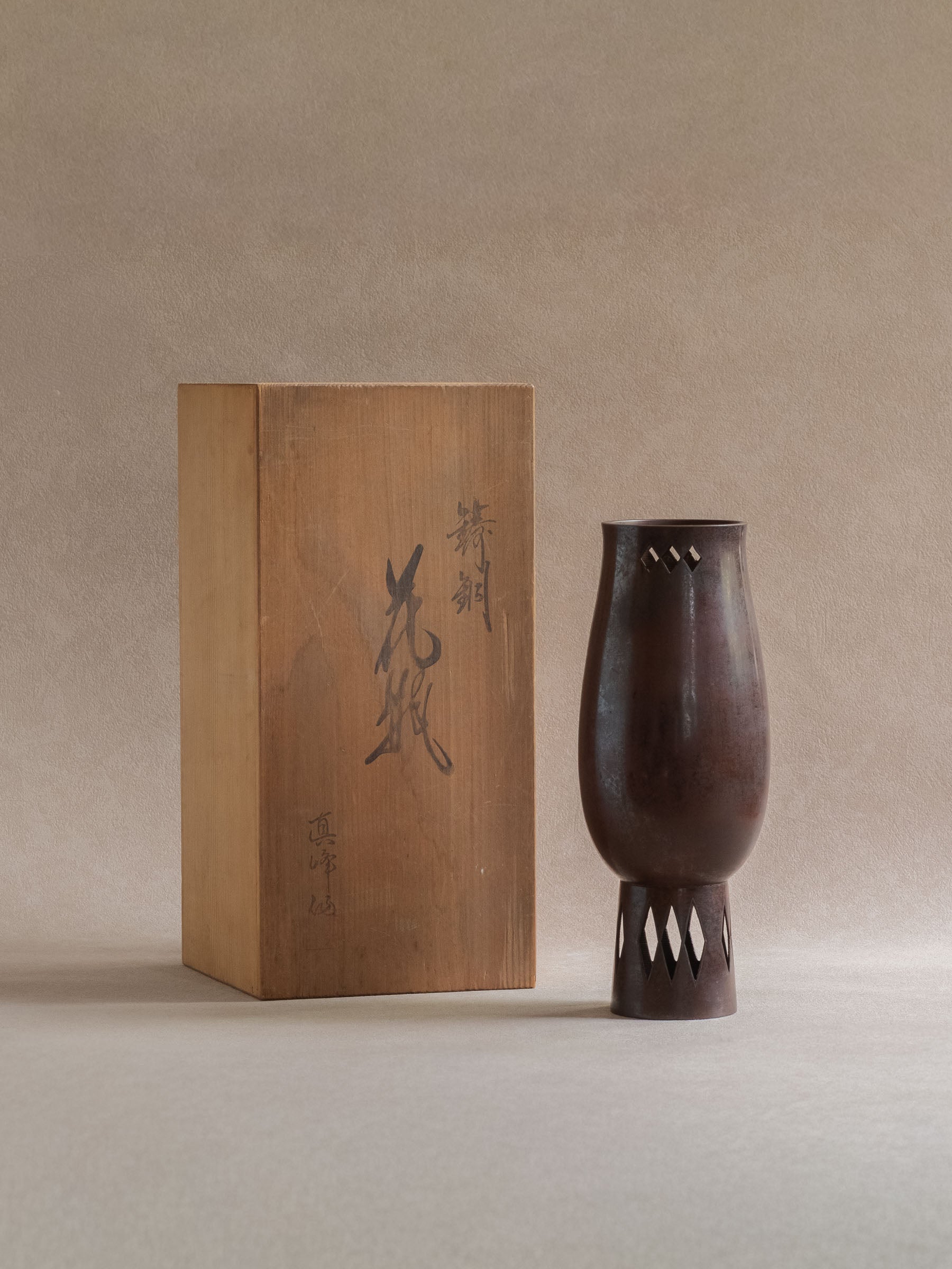 Japanese Takaoka cast copper vase displayed beside its original wooden storage box.
