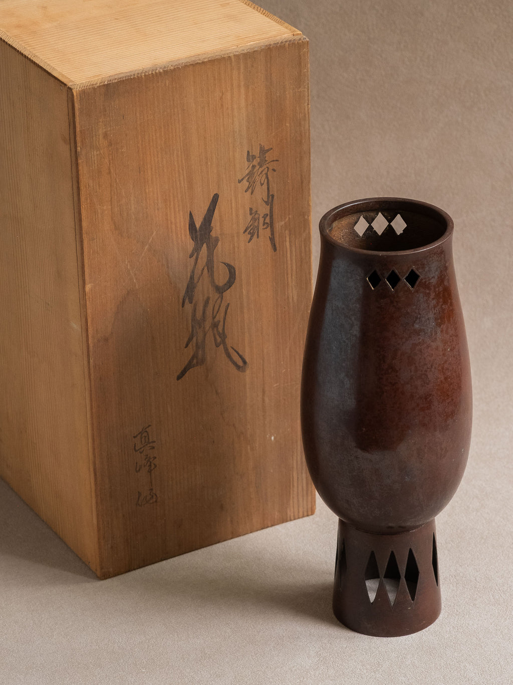 Japanese Takaoka cast copper vase shown beside its original wooden storage box with Japanese inscription.
