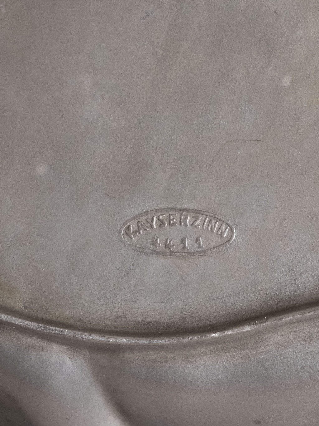 Underside of Kayserzinn pewter plate showing stamped “Kayserzinn 4411” maker’s mark.