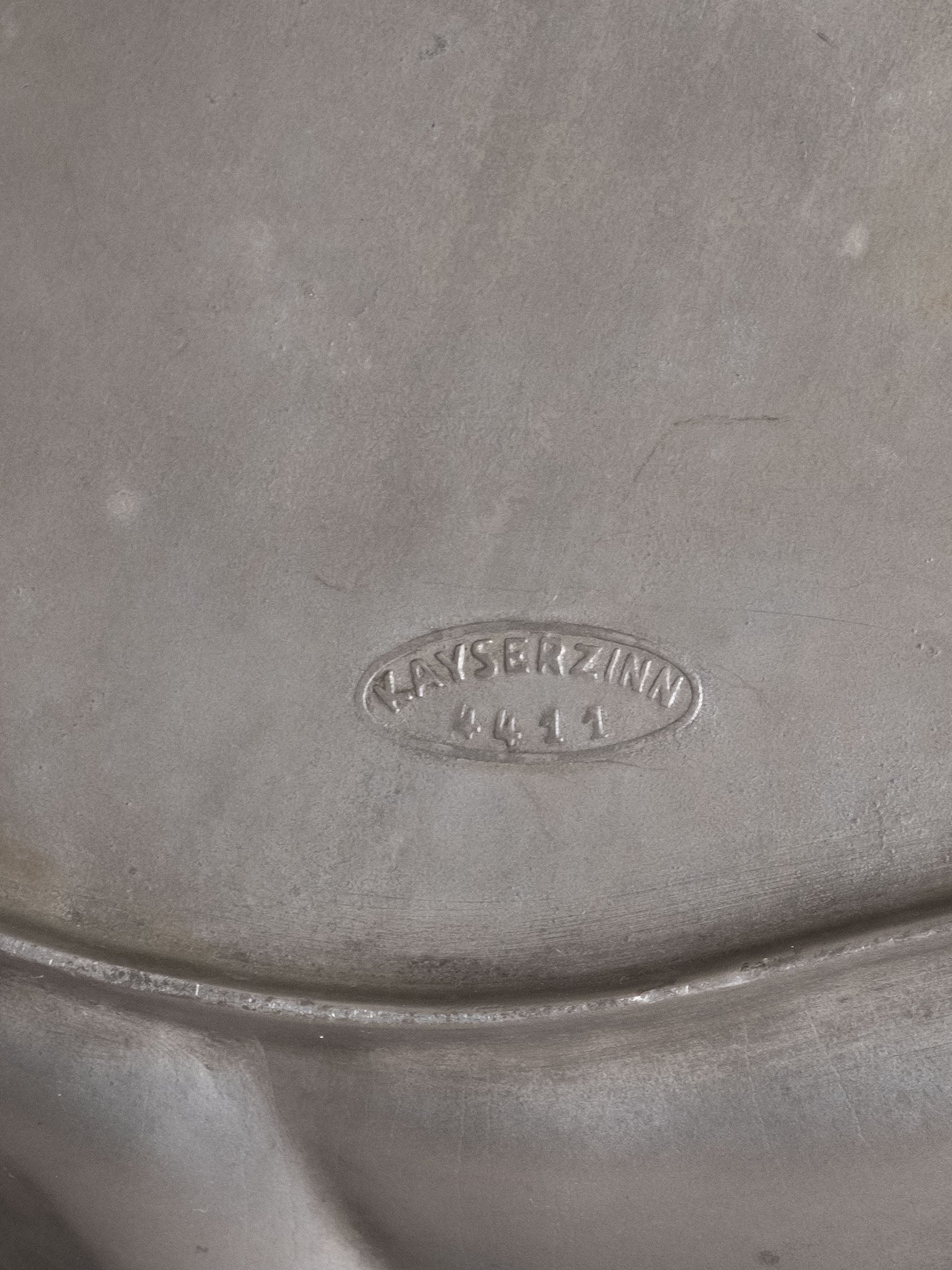 Underside of Kayserzinn pewter plate showing stamped “Kayserzinn 4411” maker’s mark.