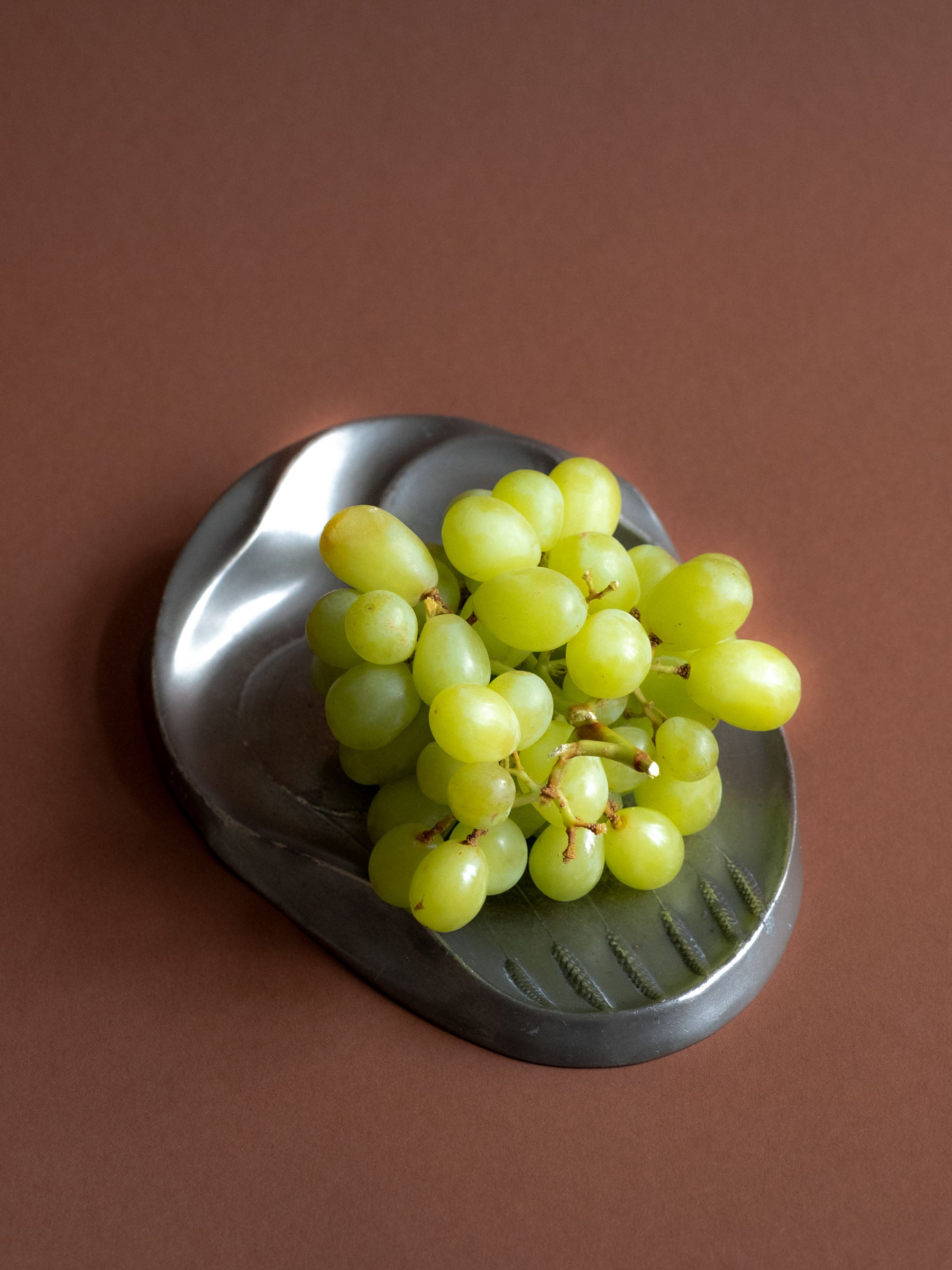 Grapes on a Kayserzinn pewter plate showing stamped “Kayserzinn 4411” maker’s mark.