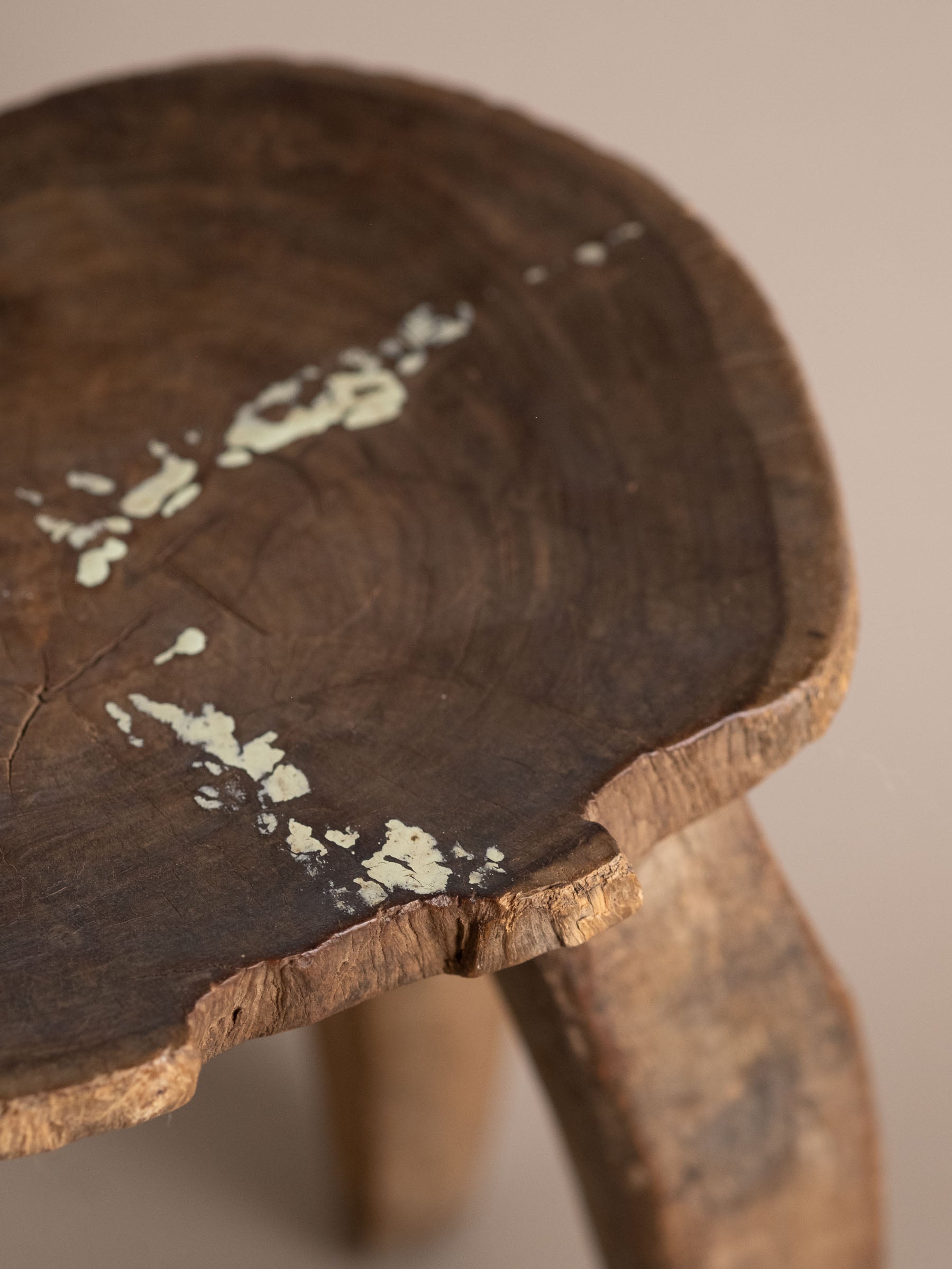 Detail of Lobi stool seat edge with natural crack, irregular carved rim, and aged wood texture.