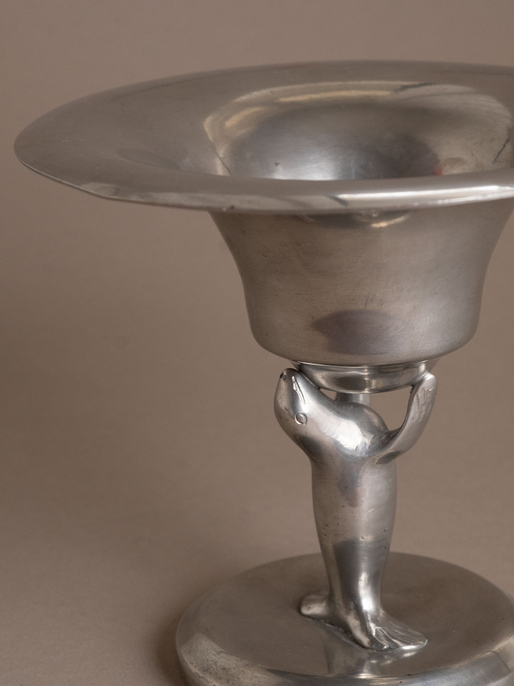 Detail of the stylised sea lion figure supporting the pewter bowl, Dahlströms Tenn, Sweden.