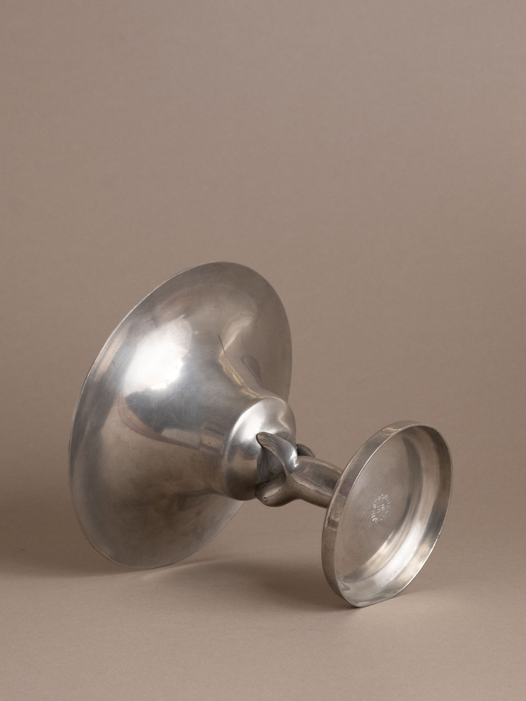 Dahlströms Tenn pewter sea lion pedestal bowl photographed on its side, showing pedestal and base.