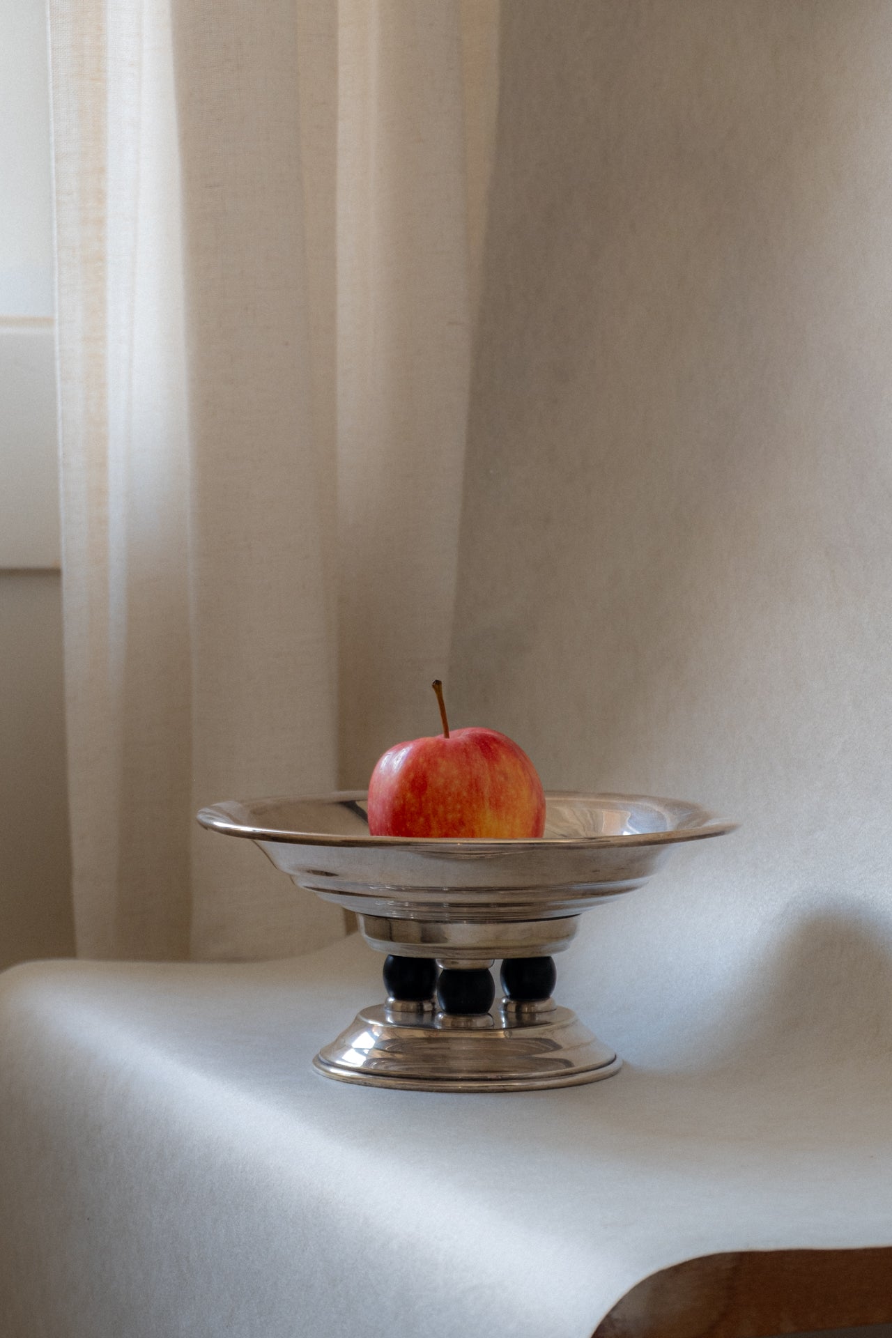 Art Deco EPNS silver pedestal tazza bowl with apple inside, natural window light setting.