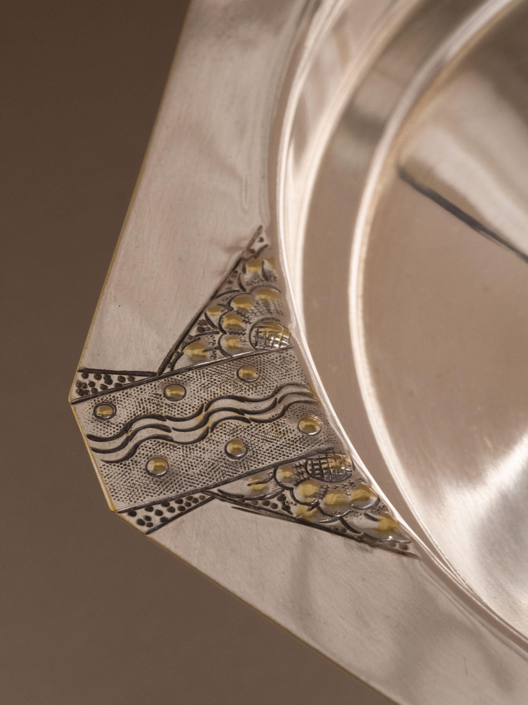 Detail of the faceted rim on the silver-plated pedestal bowl with geometric engraved ornament.