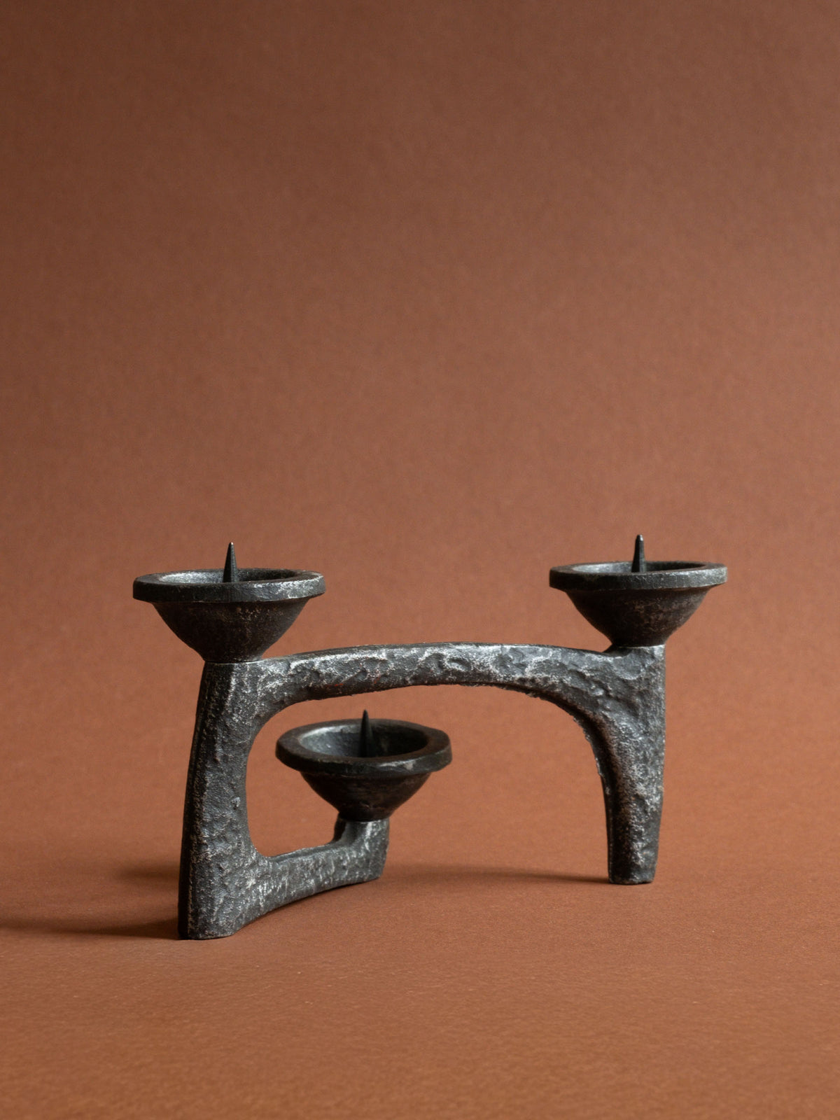 Full alternate view of the compact three-light cast iron candleholder showing its low horizontal silhouette and central bowl.