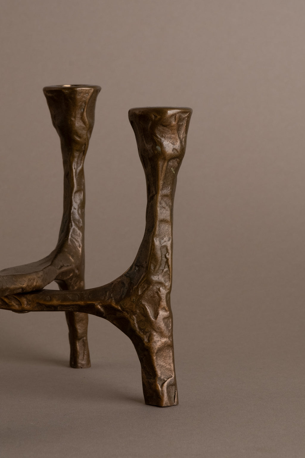 Side view of Brutalist bronze four-arm candleholder showing sculptural cross-braced form, Germany, 1970s.
