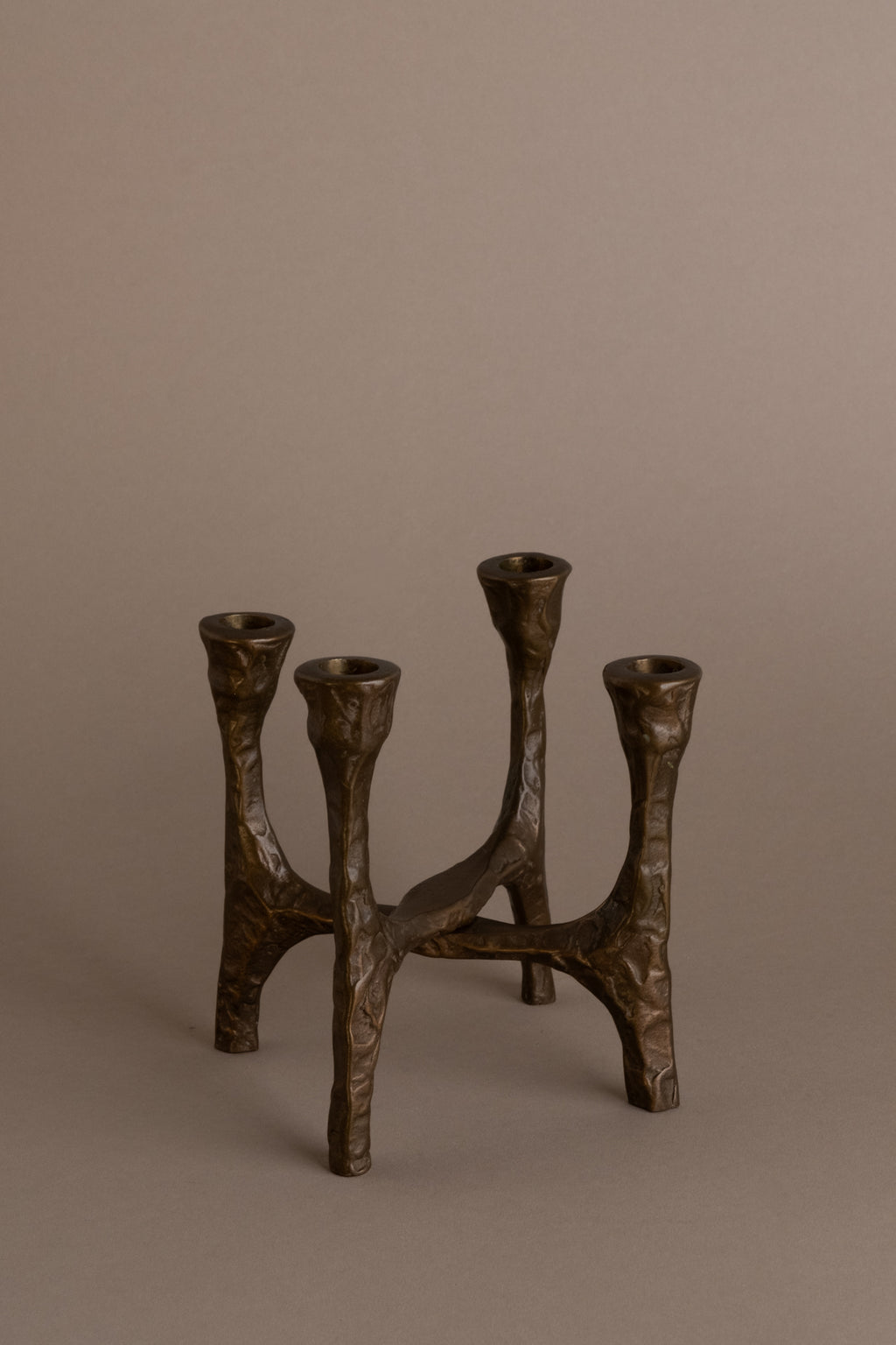 Brutalist four-arm bronze candleholder, Germany, 1970s, full view on neutral background.