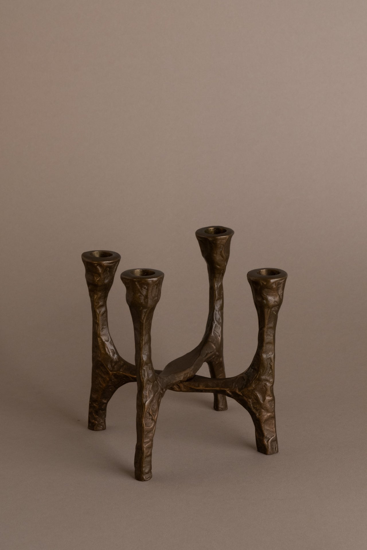 Brutalist four-arm bronze candleholder, Germany, 1970s, full view on neutral background.