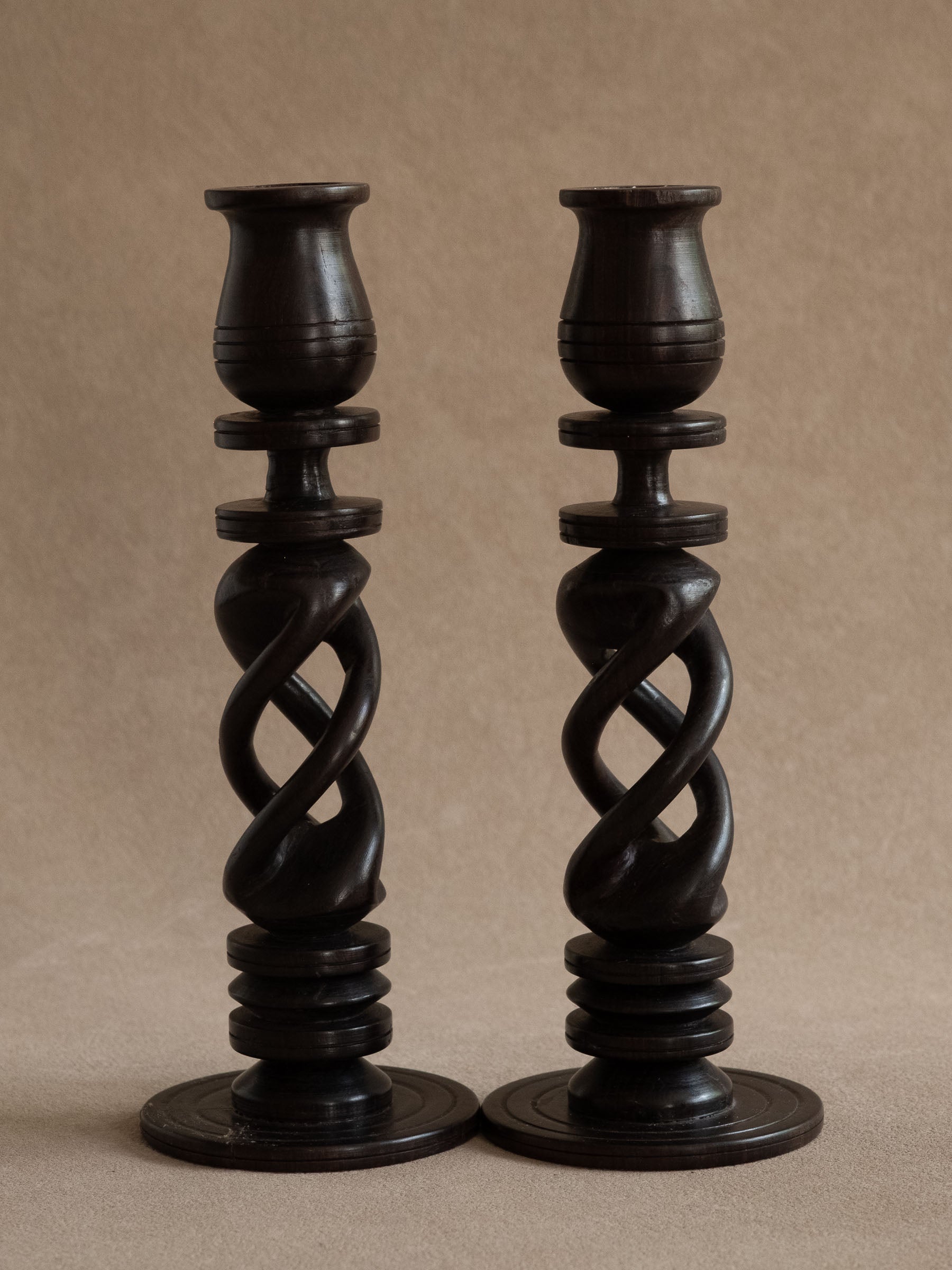 Pair of openwork ebony candleholders from Uganda, shown together against a warm neutral background.