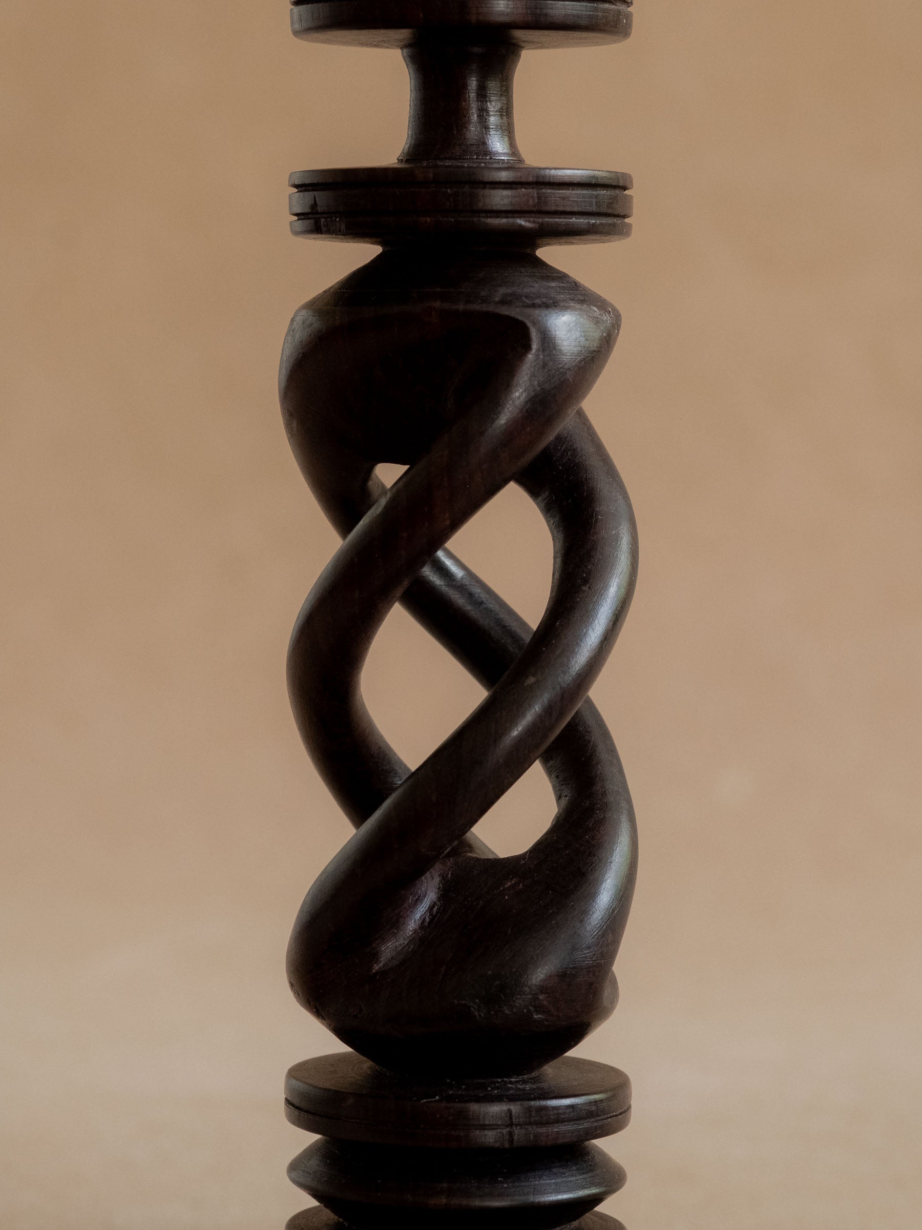 Detail of the carved openwork twist on one ebony candleholder, showing the dark polished wood surface.
