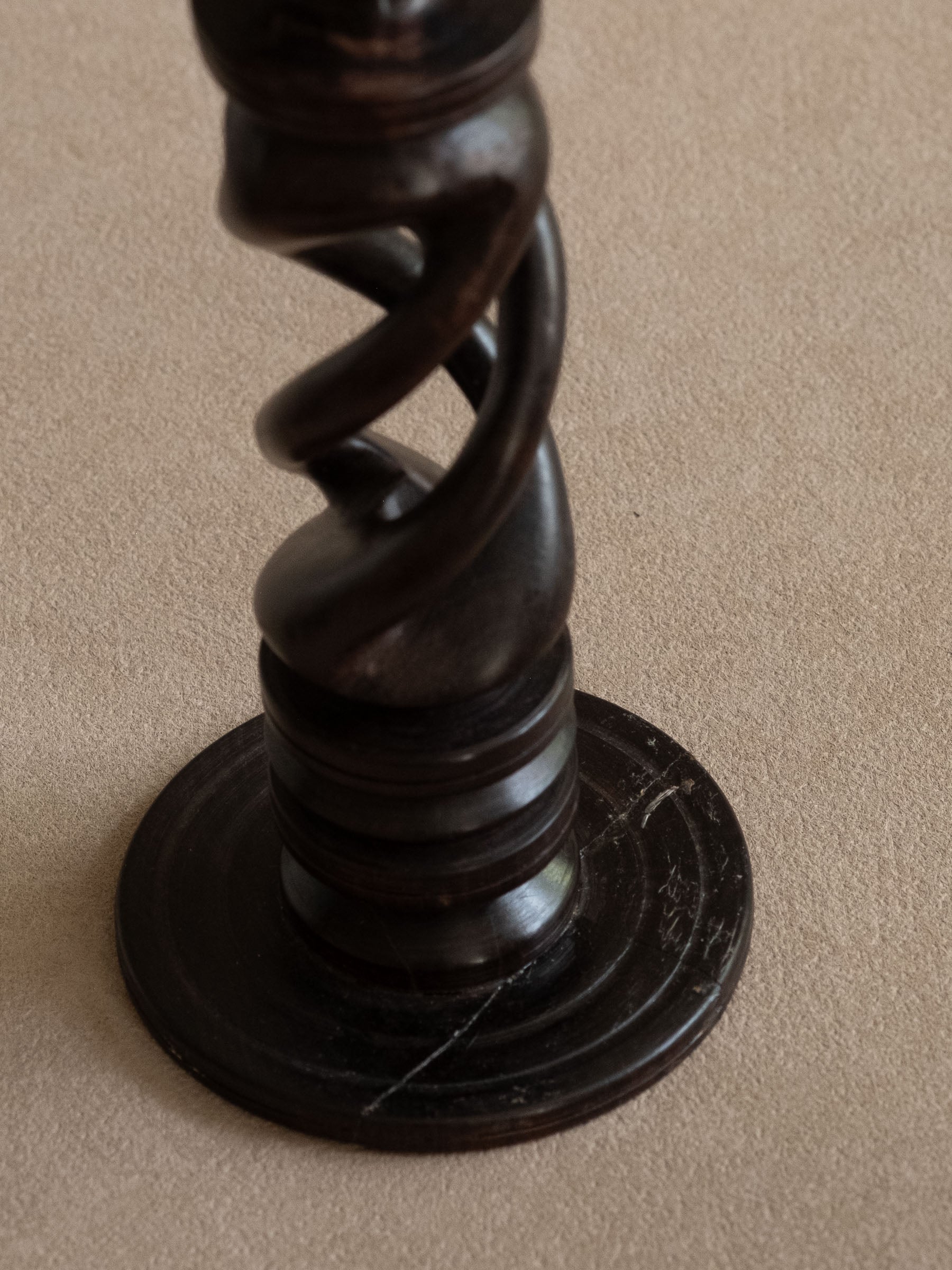 Base detail of one ebony candleholder showing age-related scratches and wear.