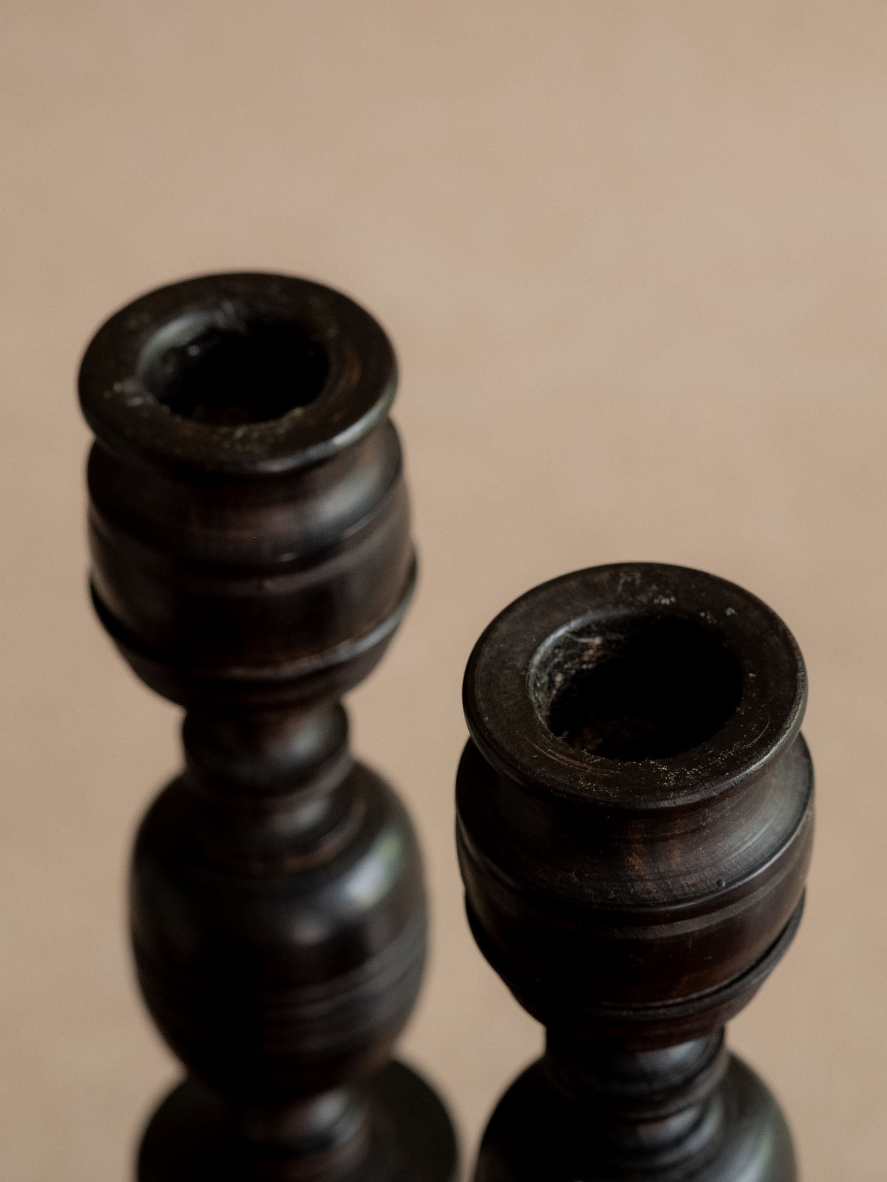 Close view of the two ebony candleholder cups, showing the turned rims and dark wood surface.
