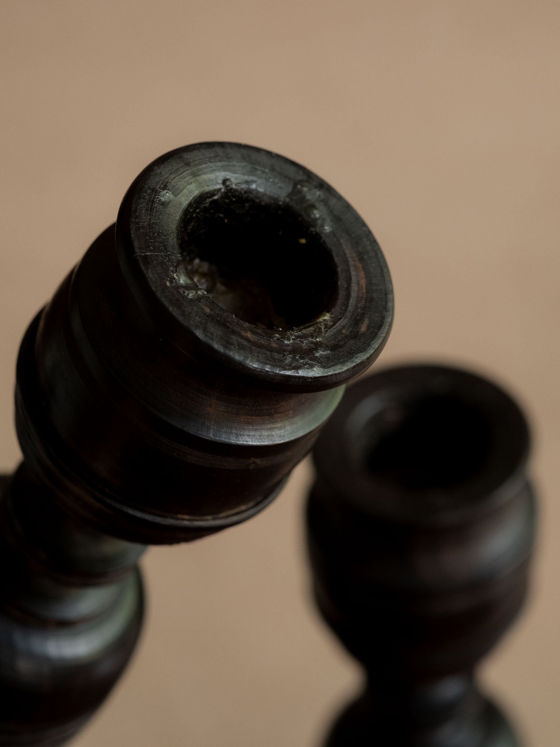 Detail of one turned ebony candle cup with the second candleholder softly behind it.