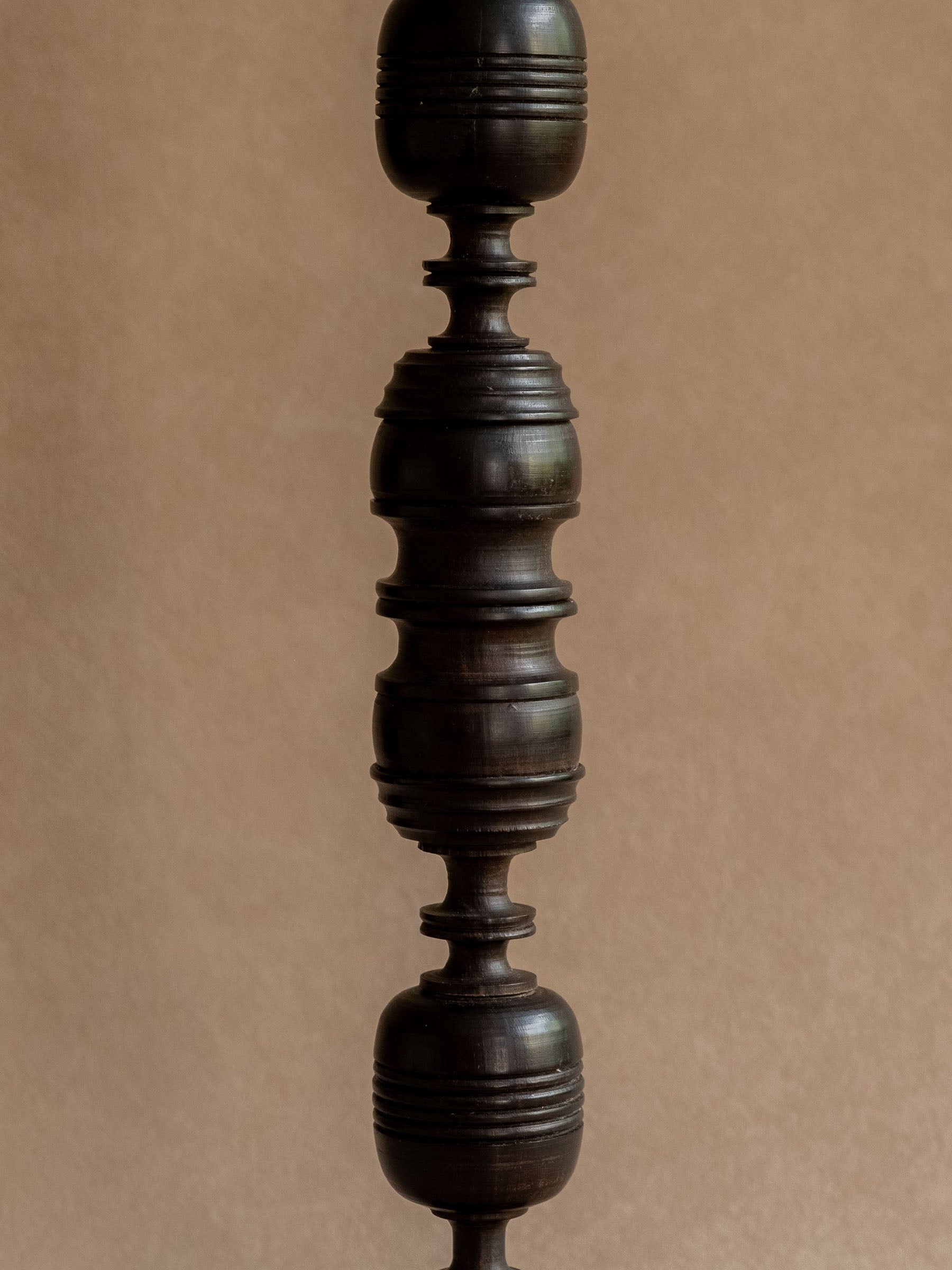 Side detail of a turned ebony candleholder showing the stacked rounded sections and carved grooves.
