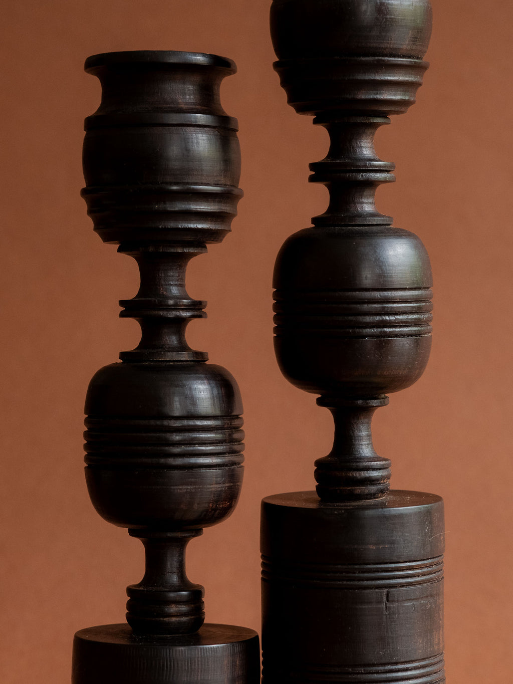 Close front detail of the paired ebony candleholders showing their rounded turned sections and groove patterns.