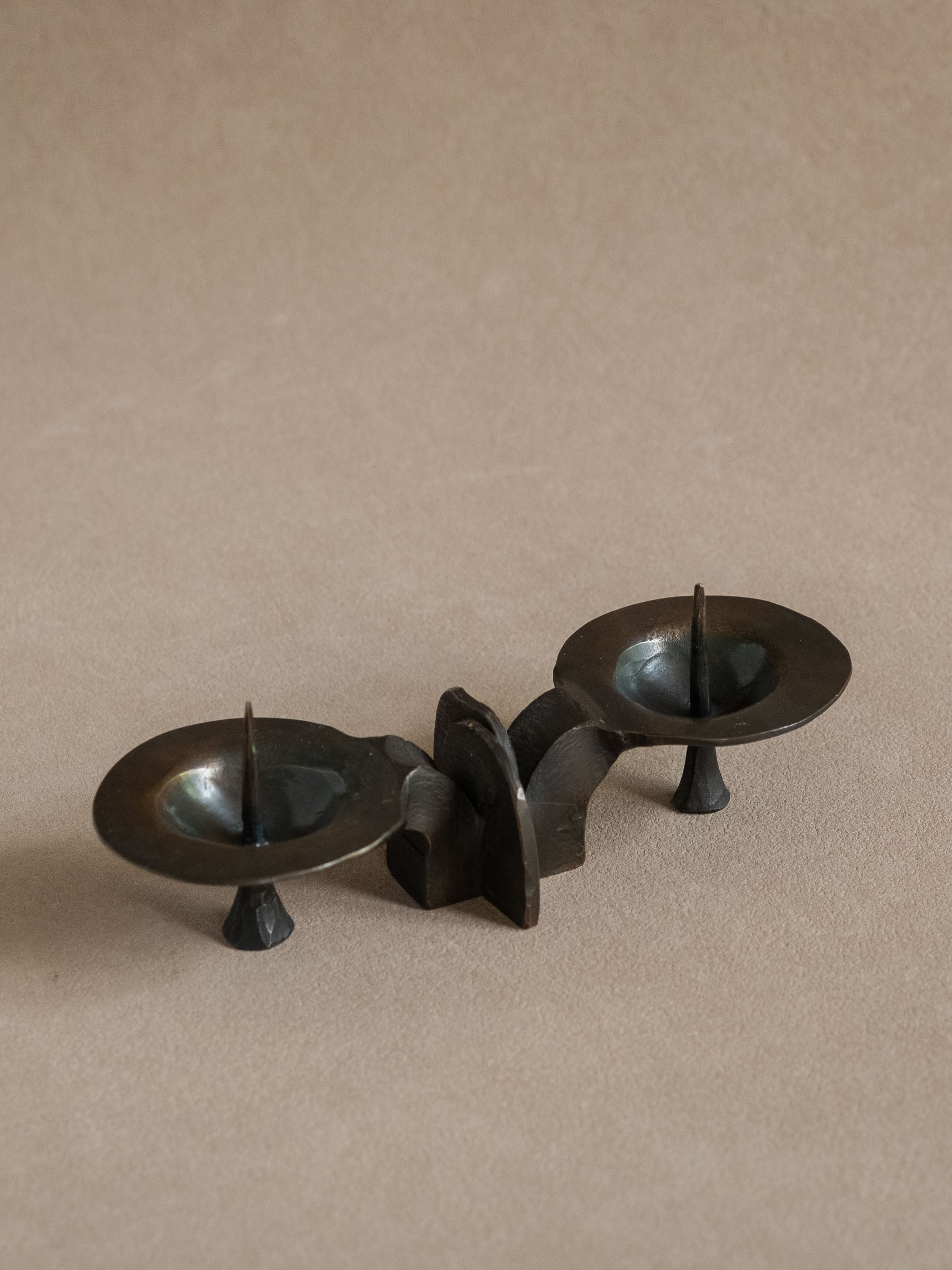 Attributed Kunstschmiede Bergmeister two-light bronze candleholder shown from a three-quarter angle.