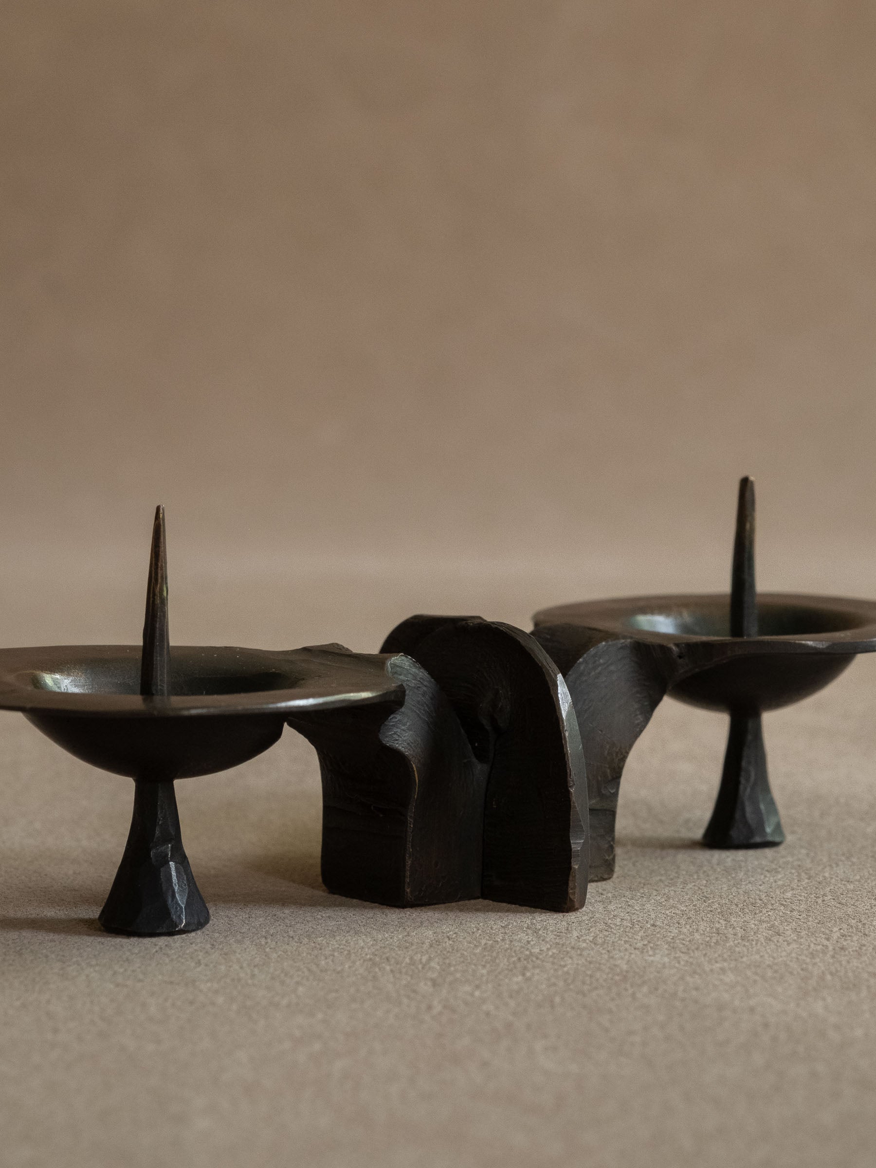 Close front detail of the candleholder showing the central folded bronze construction between the two candle plates.