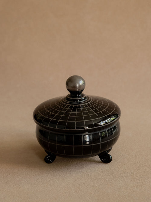 Black Hyalith glass Art Deco box from France shown closed, with silver-coloured grid decoration and ball finial.