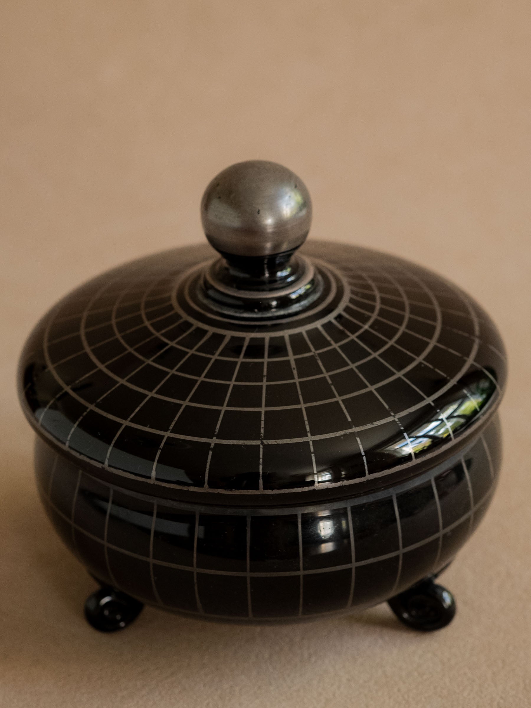 Closer view of the closed black Hyalith glass box showing the rounded body, feet and silver-coloured line decoration.