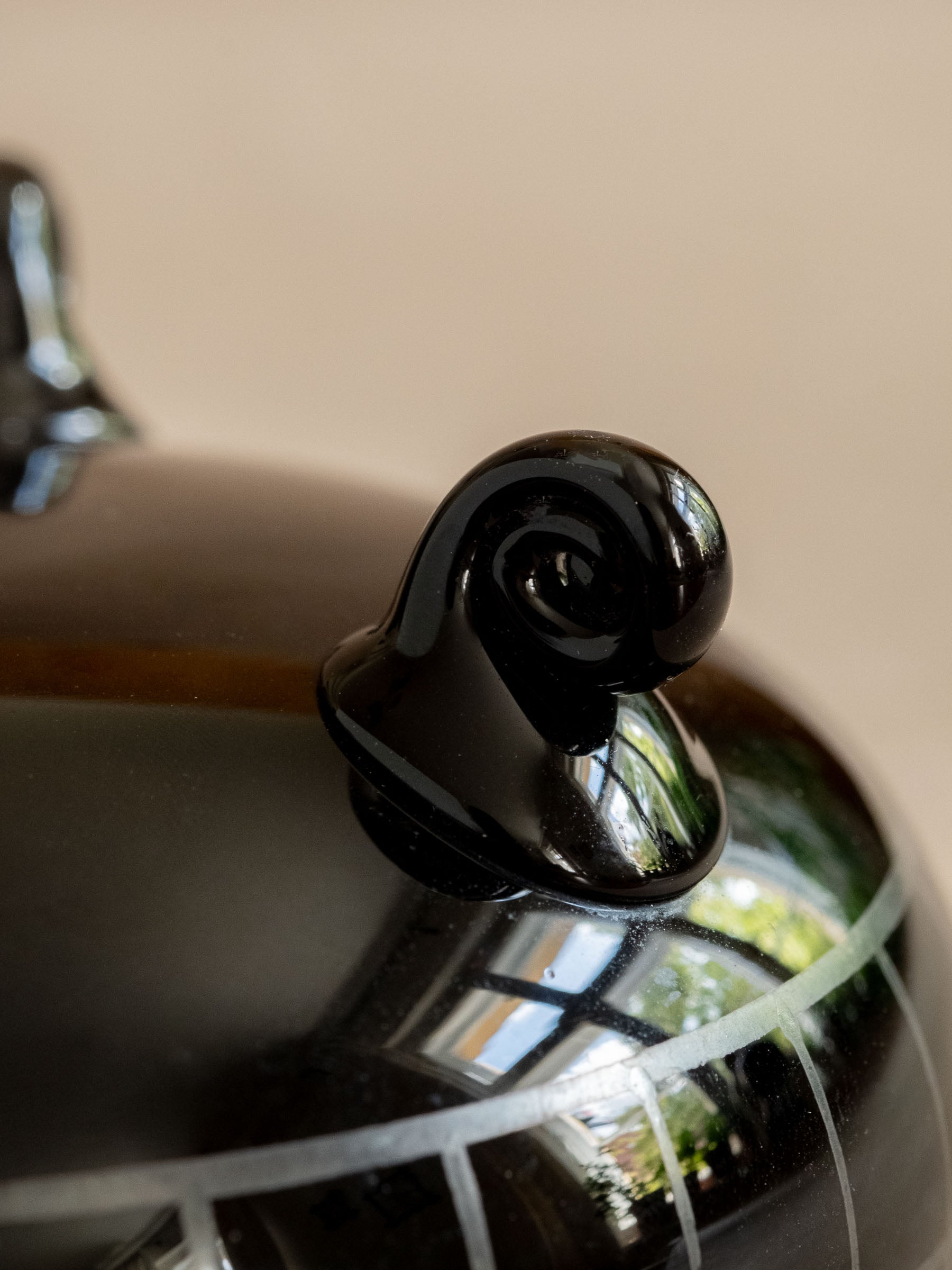 Close detail of one curled glass foot and the silver-coloured decoration on the black Hyalith box.