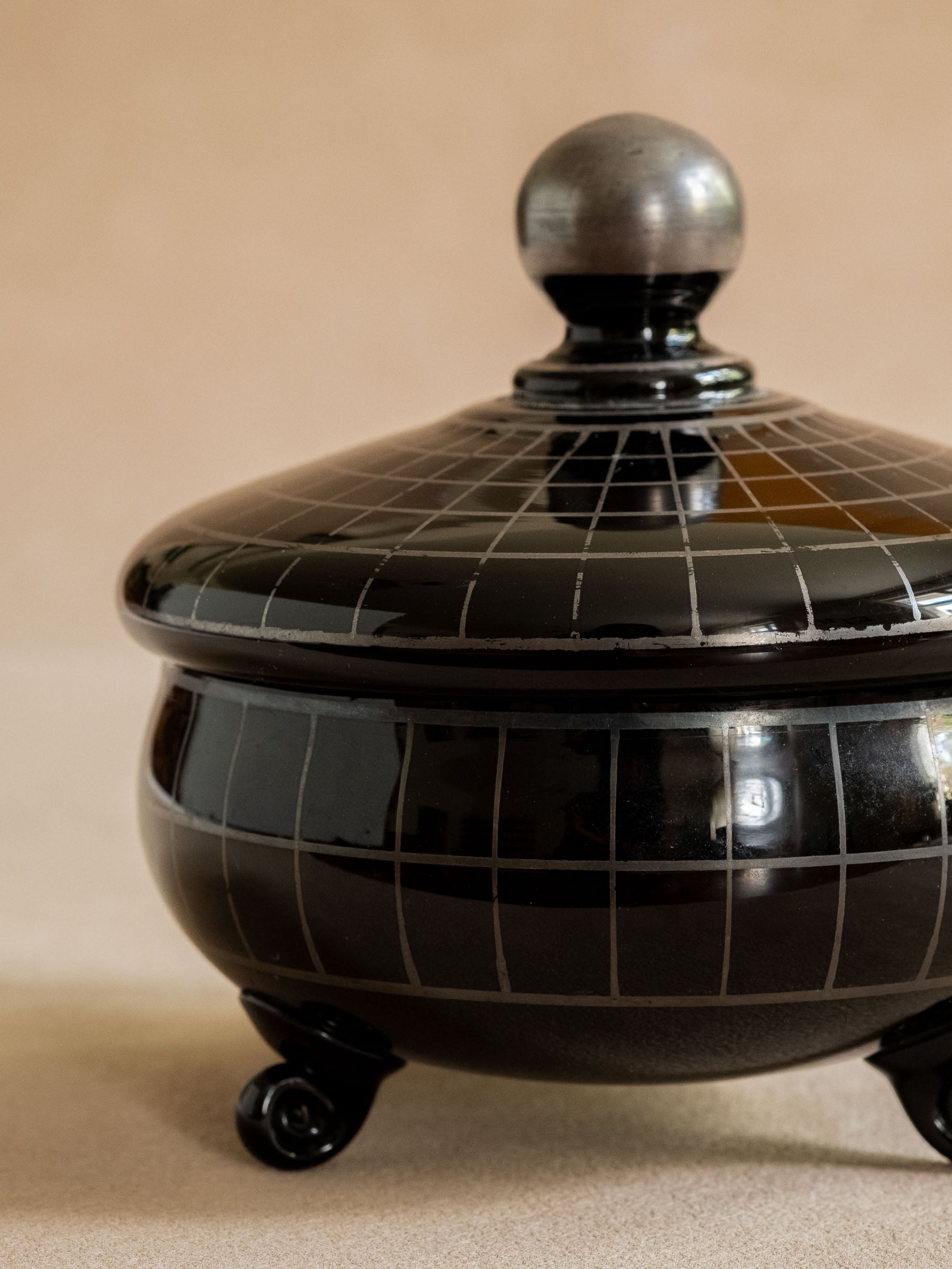 Close front detail of the black glass box showing the silver-coloured grid pattern, lid edge and ball finial.