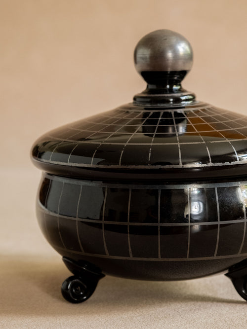 Close front detail of the black glass box showing the silver-coloured grid pattern, lid edge and ball finial.