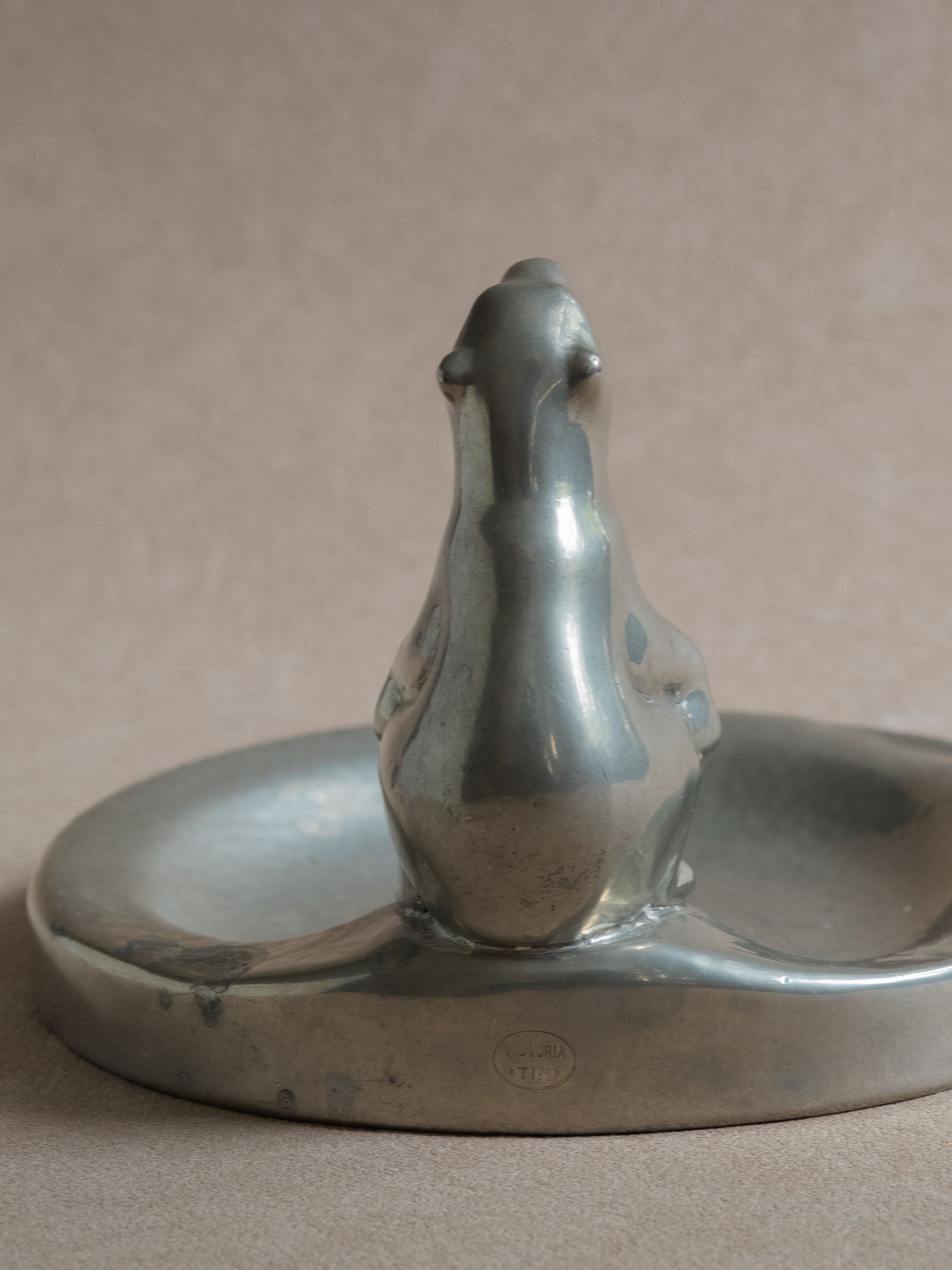 Close-up rear view of a pewter polar bear figural dish, showing the standing bear figure and Victoria Tin mark on the side of the shallow dish.
