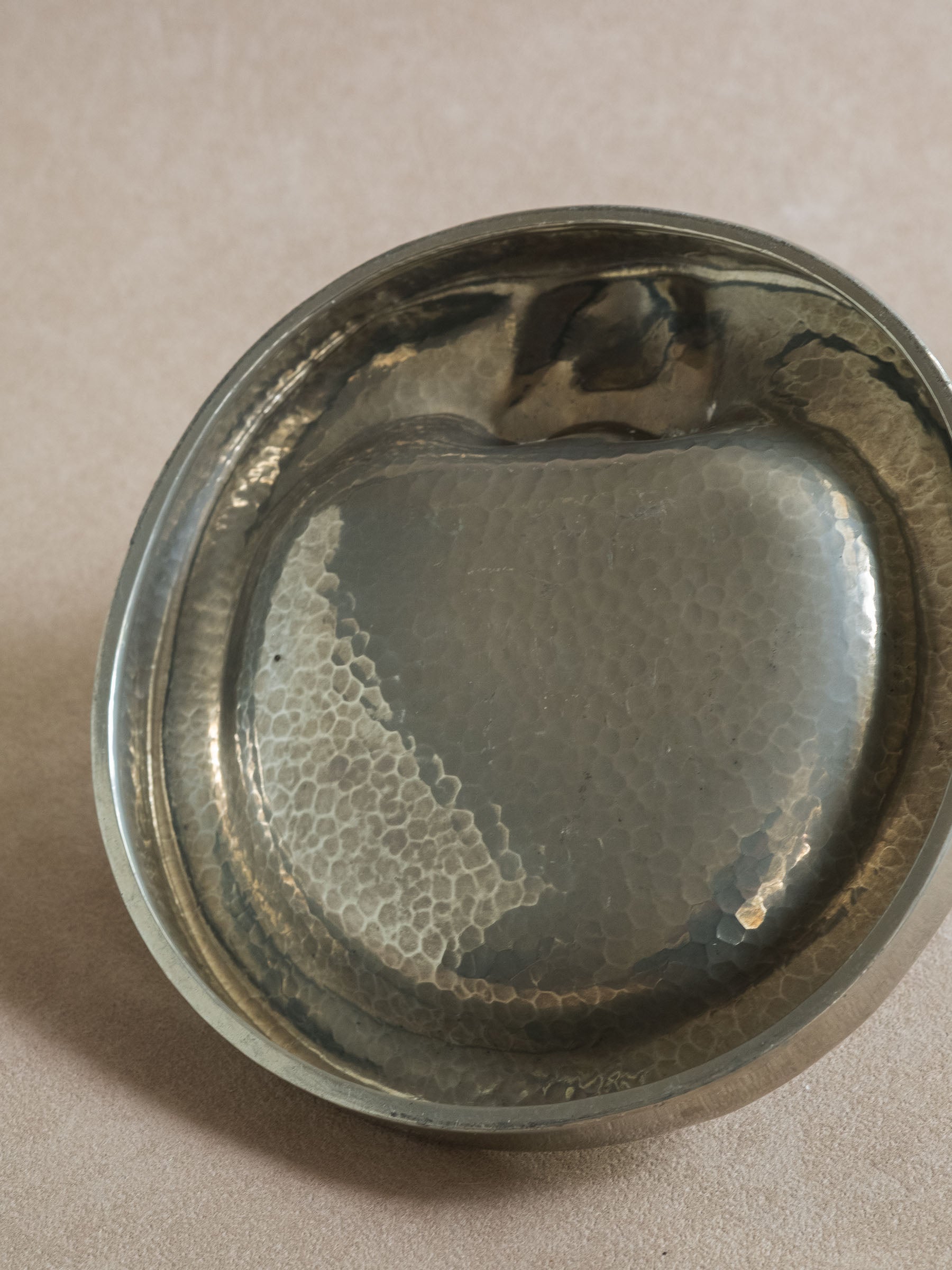 Side view of a pewter polar bear figural dish, with the bear figure positioned at the edge of the shallow bowl.
