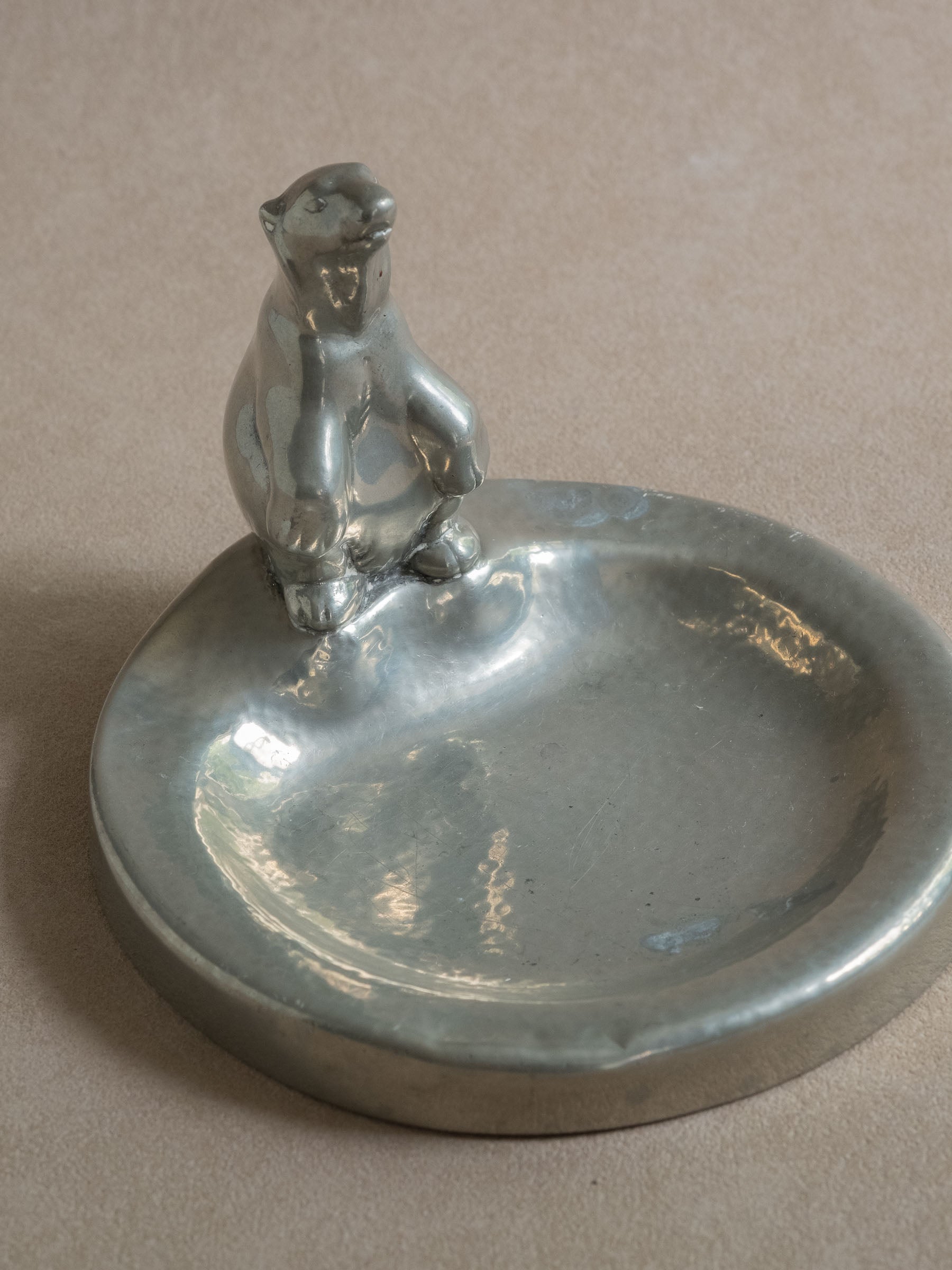 Angled front view of a pewter polar bear figural dish, showing the rounded shallow bowl and standing bear figure.
