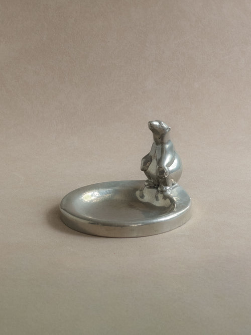 Wide view of a pewter polar bear figural dish, showing the small sculptural bear detail and shallow circular dish.
