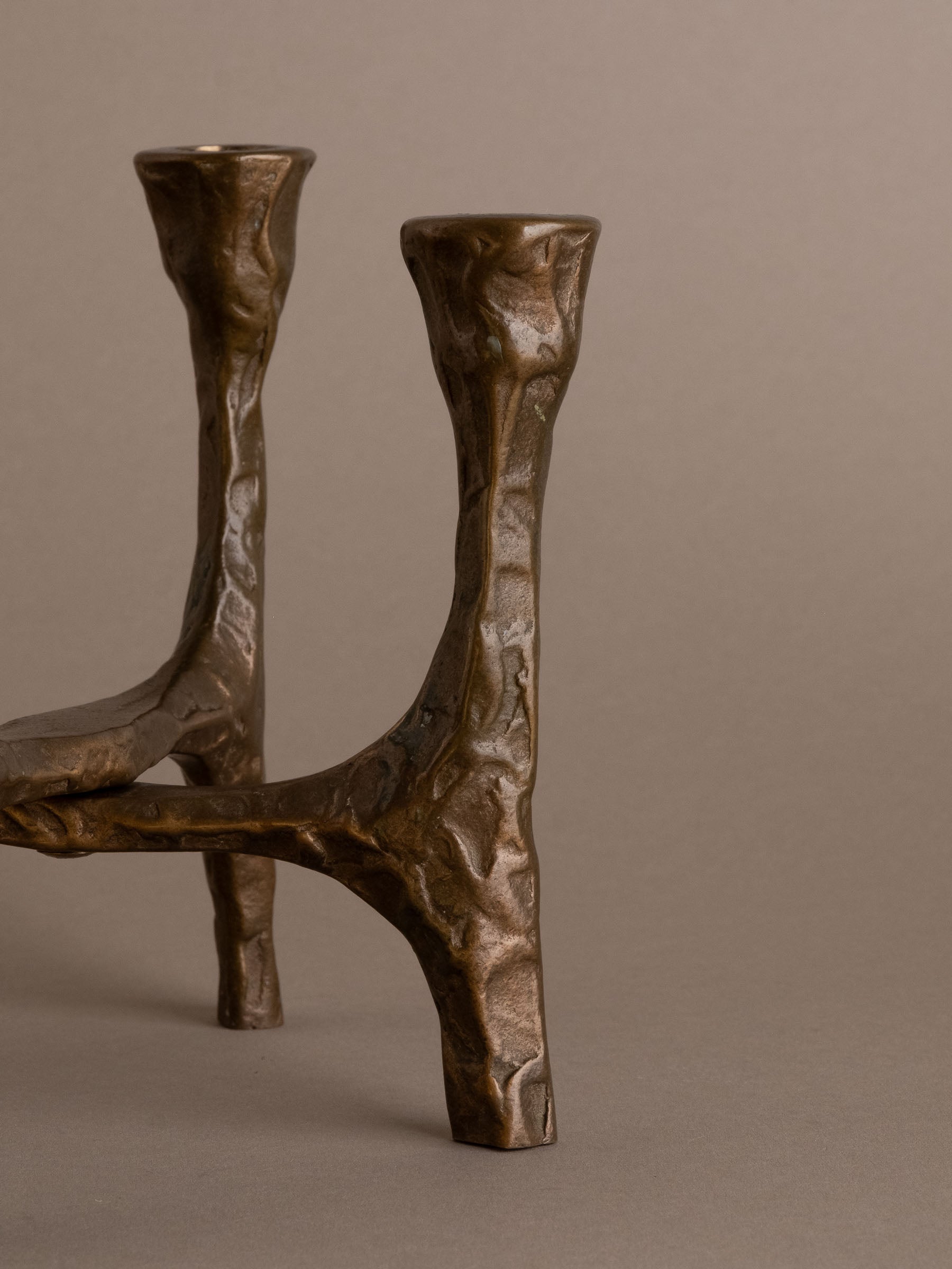 Side view of Brutalist bronze four-arm candleholder showing sculptural cross-braced form, Germany, 1970s.