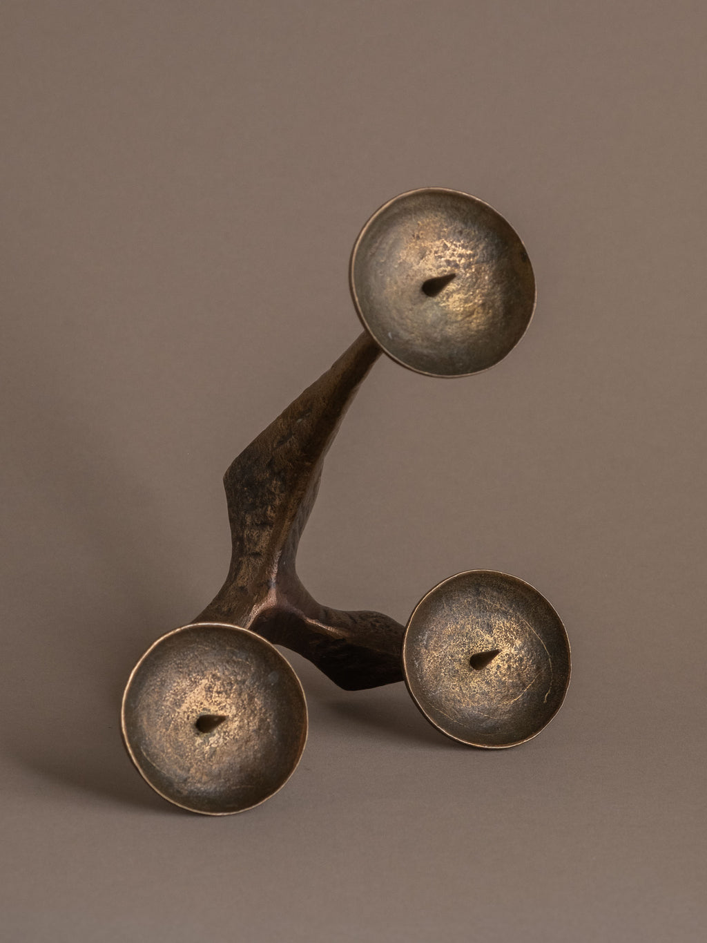 Three-arm bronze candleholder viewed from above, showing circular drip trays and branching arms.